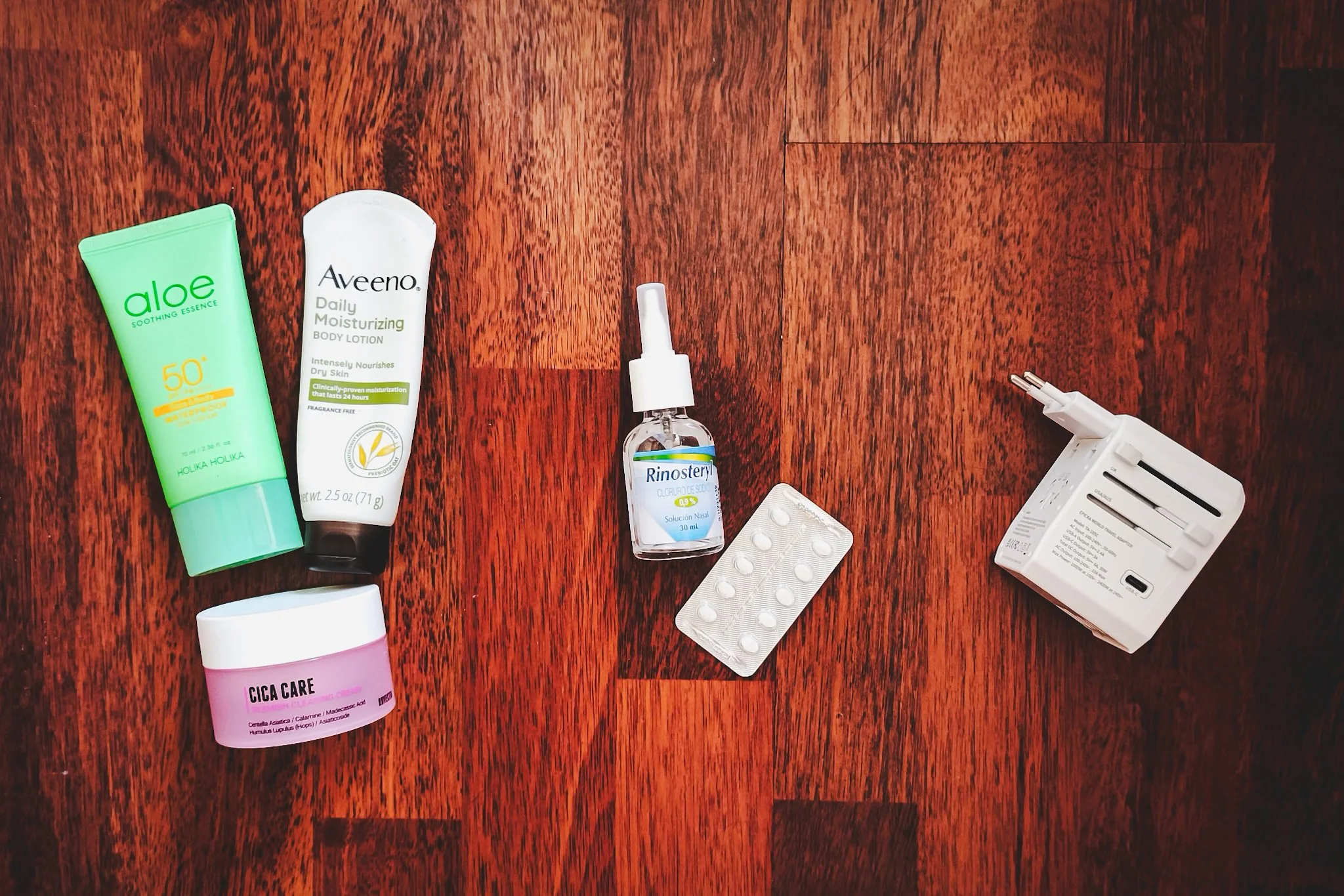 Flat lay of essentials for skin, sun, health, and tech.