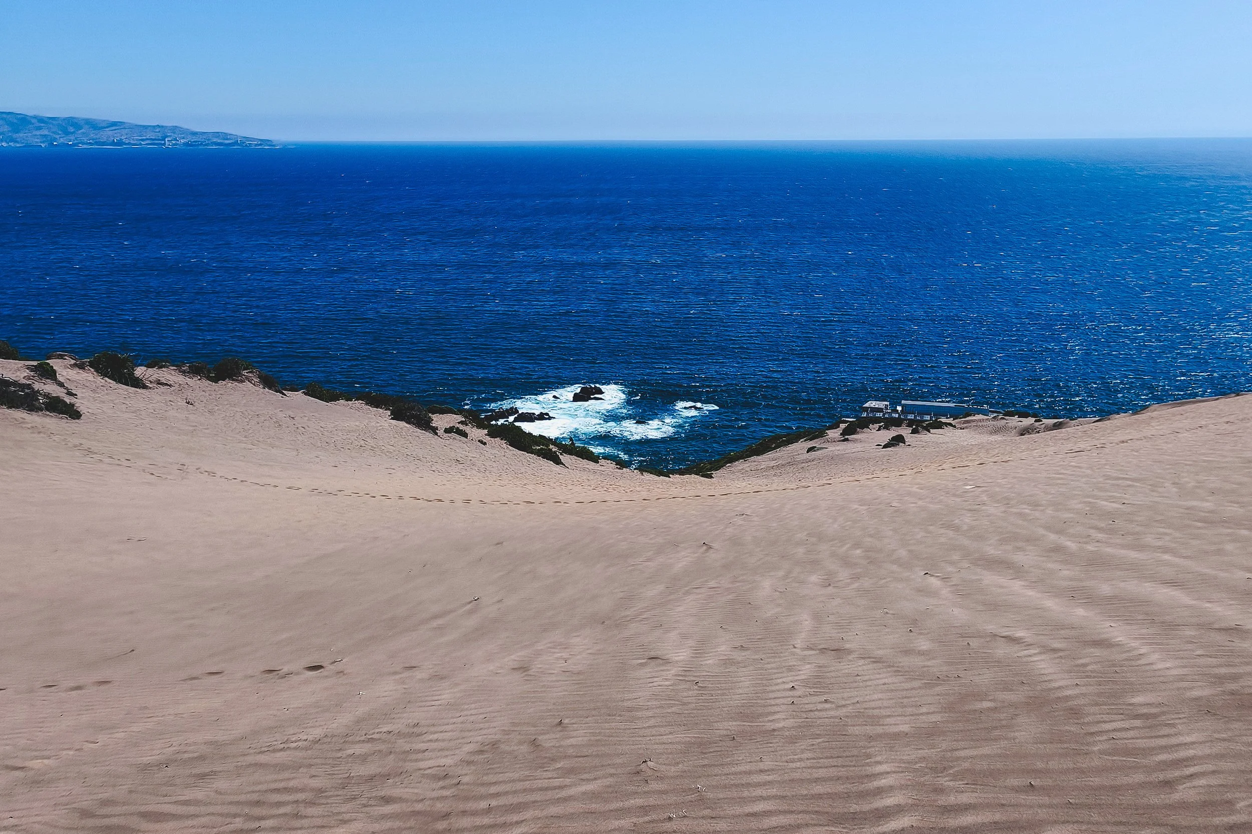 Sand cliff down to the ocean at Concón Dunes.