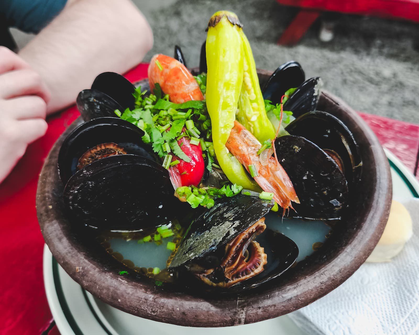 Bowl of paila marina filled with mussels, shellfish, fish, and prawns.
