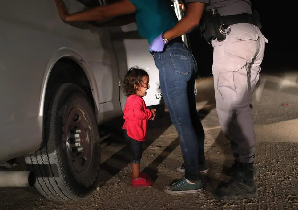 A two-year-old Honduran asylum seeker cries as her mother is searched and detained near the U.S.-Mexico border (John Moore/Getty Images)