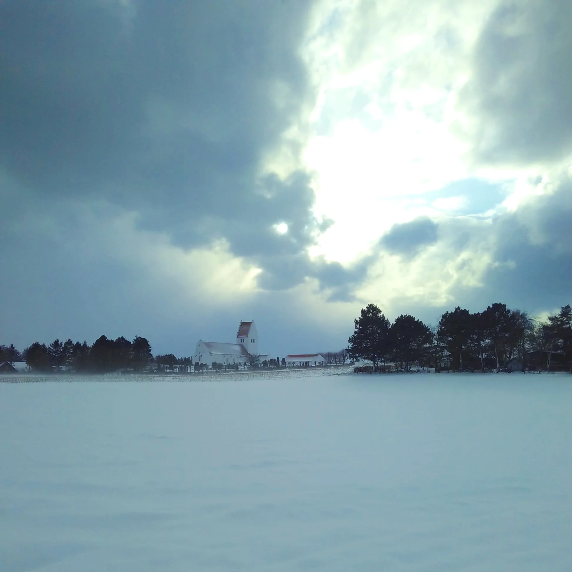 Fanefjord Kirke set fra gården i dramatisk januarlys.