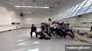 group of dancers heave across a studio