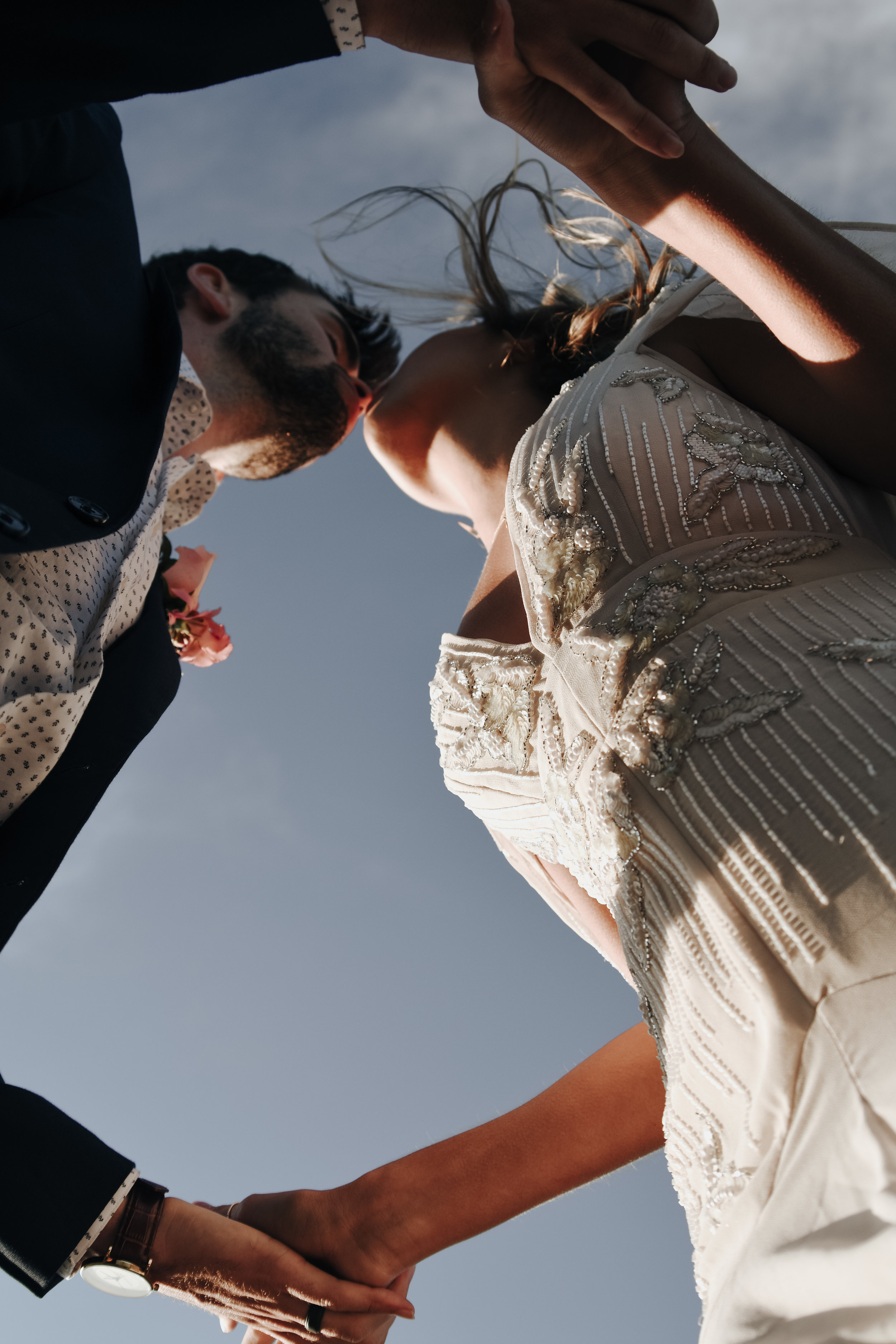  An image from below of a couple who have eloped, standing outdoors as they hold hands and lean in to kiss by Vanessa Venable - Asheville elopement photographer 