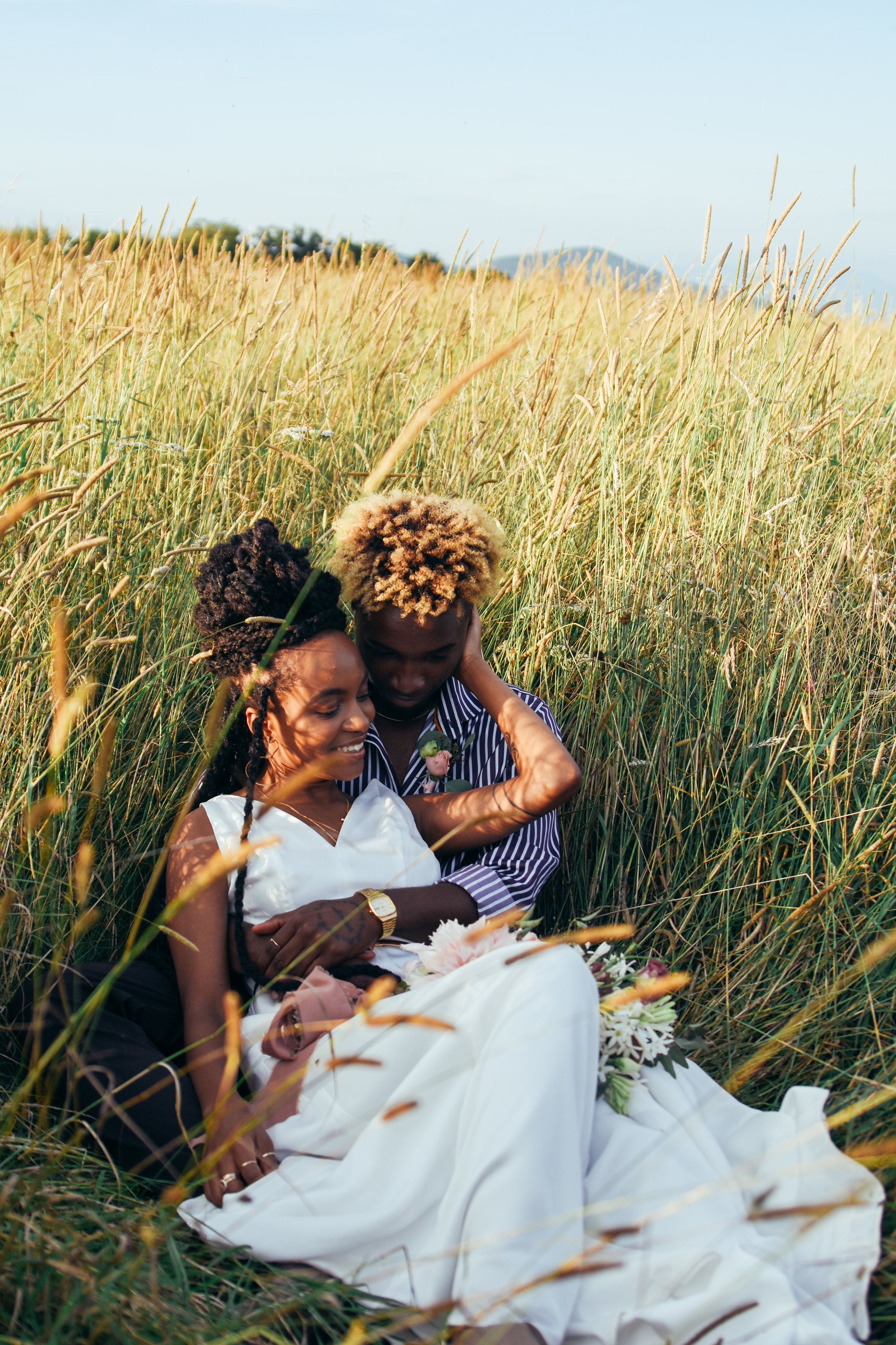  A couple enjoying their elopement lay down in tall grass and hold each other romantically on Max Patch Mountain near Charlotte, NC 