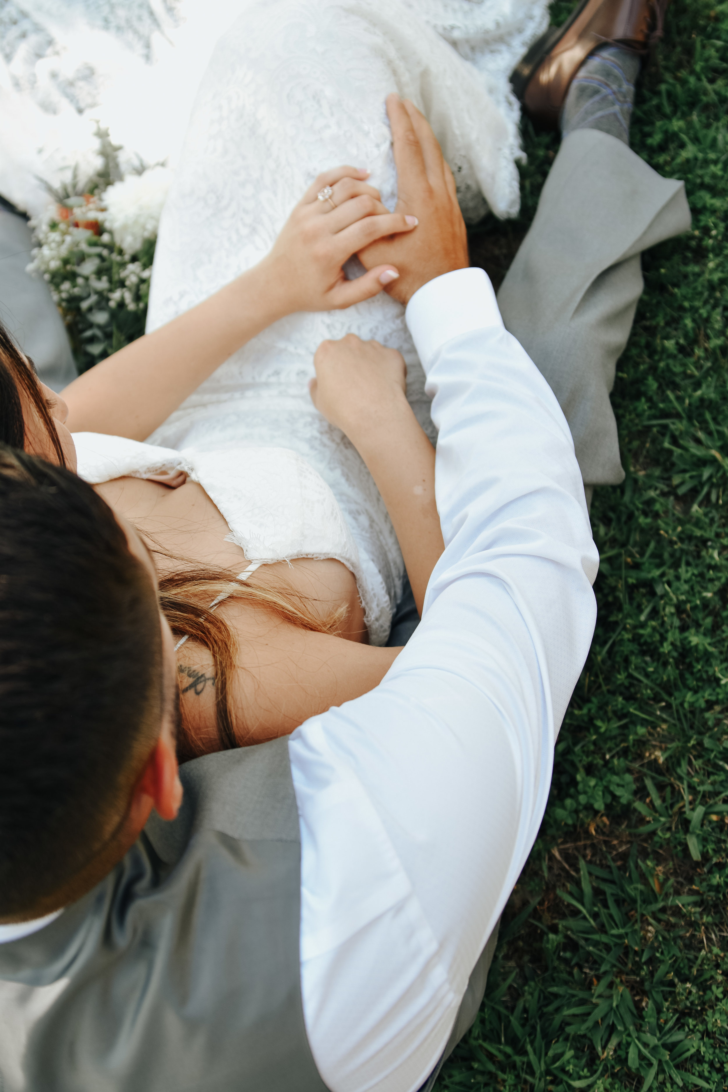  A photograph from above of a couple who have eloped, with the bride leaning back against her partner as they hold hands and romantically embrace outdoors in the grass in Marshall Park by Vanessa Venable - Charlotte NC elopement photography 