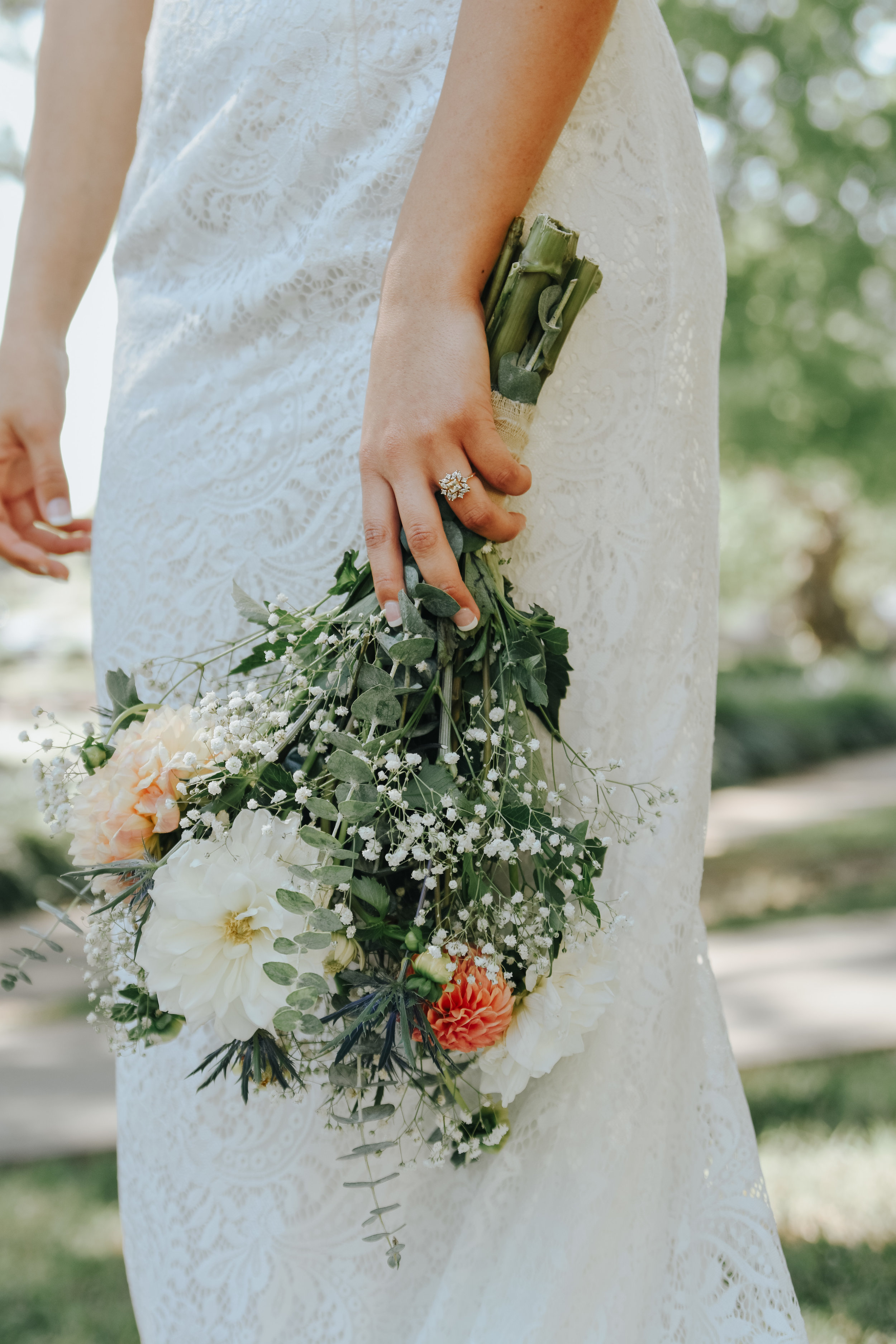  An image of a closeup view of a bride holding her beautiful bouquet just after her elopement, showing her new wedding ring on her hand at a Charlotte courthouse elopement 