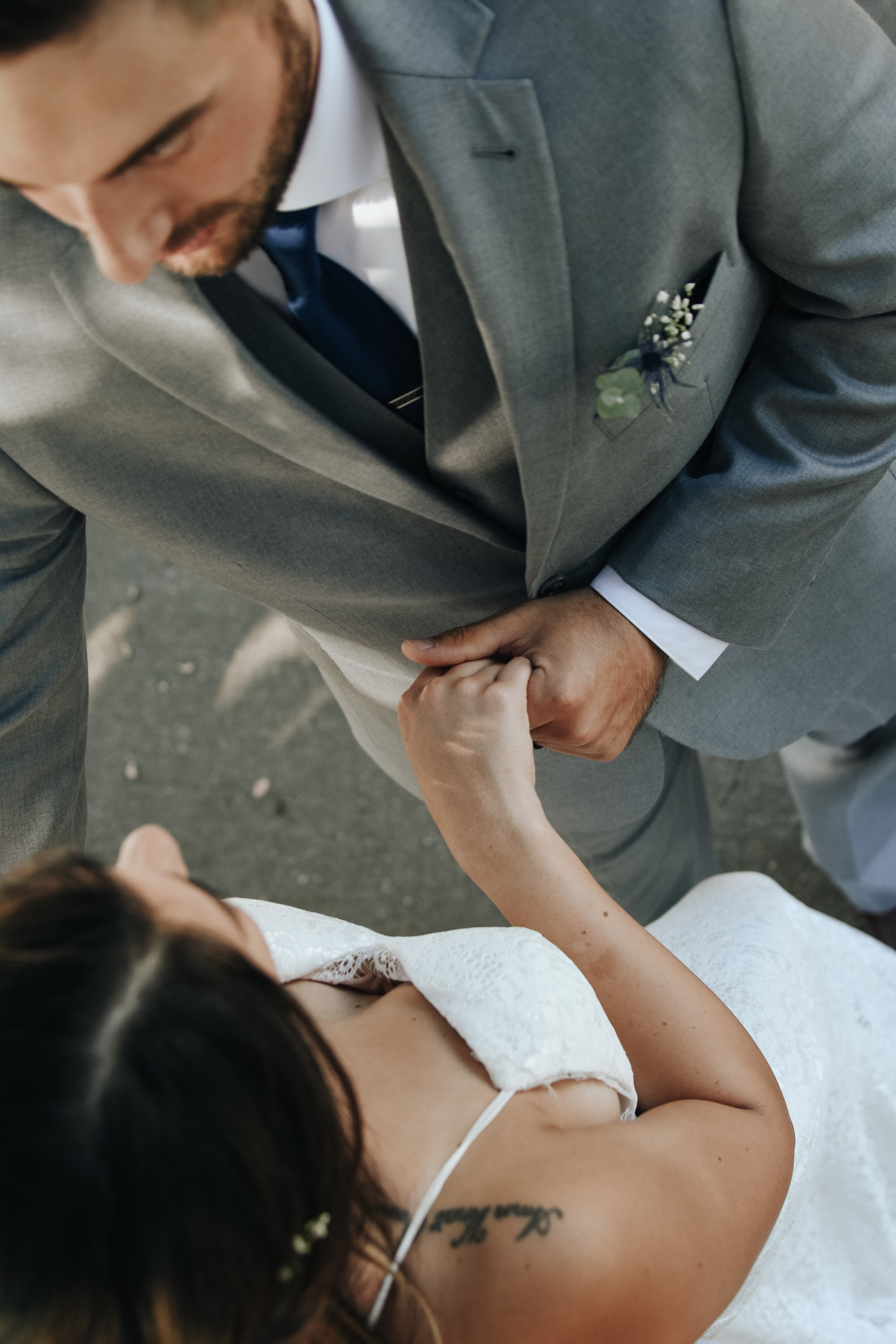  A photograph of a bride and groom tenderly embracing shortly after their elopement as they stand outdoors under a tree in the sunlight and shadows Mecklenburg County Courthouse elopement 