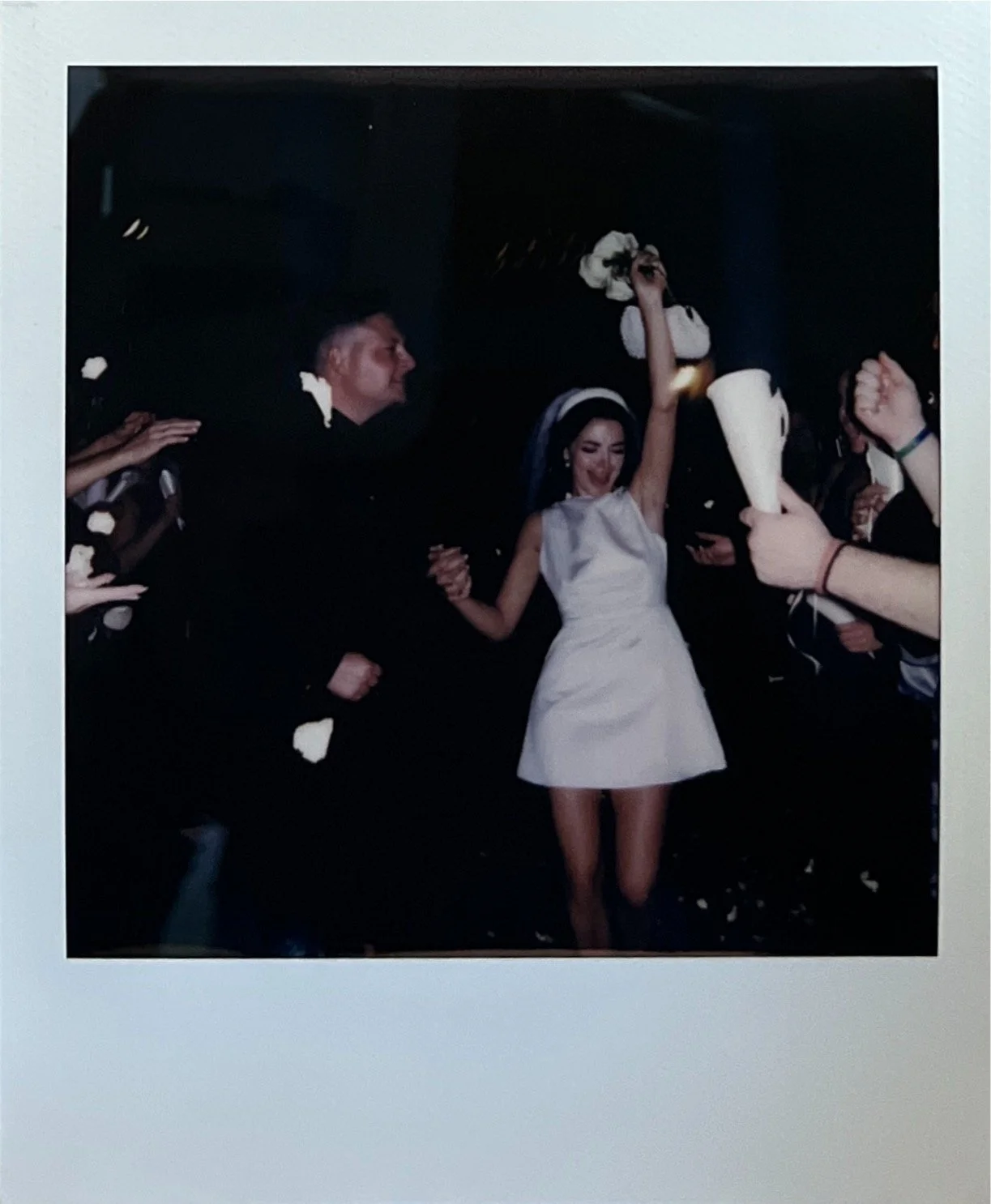 Bride throwing bouquet at wedding celebration, surrounded by guests.