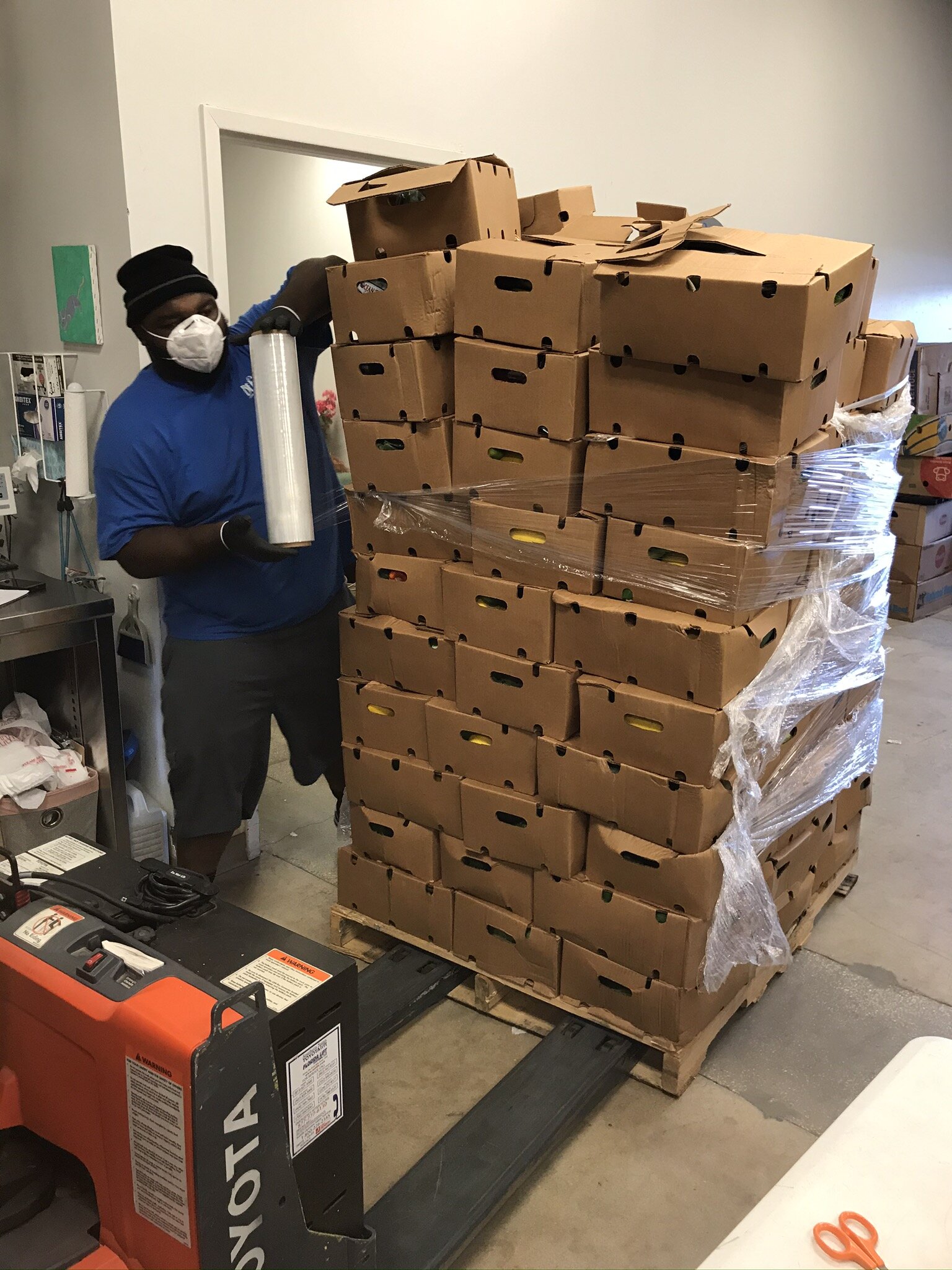 BEAM employee, Zee, stacks and wraps a large pallet of pre-packaged fresh produce, which will be distributed to partner agencies who serve high-risk seniors at the beaches.