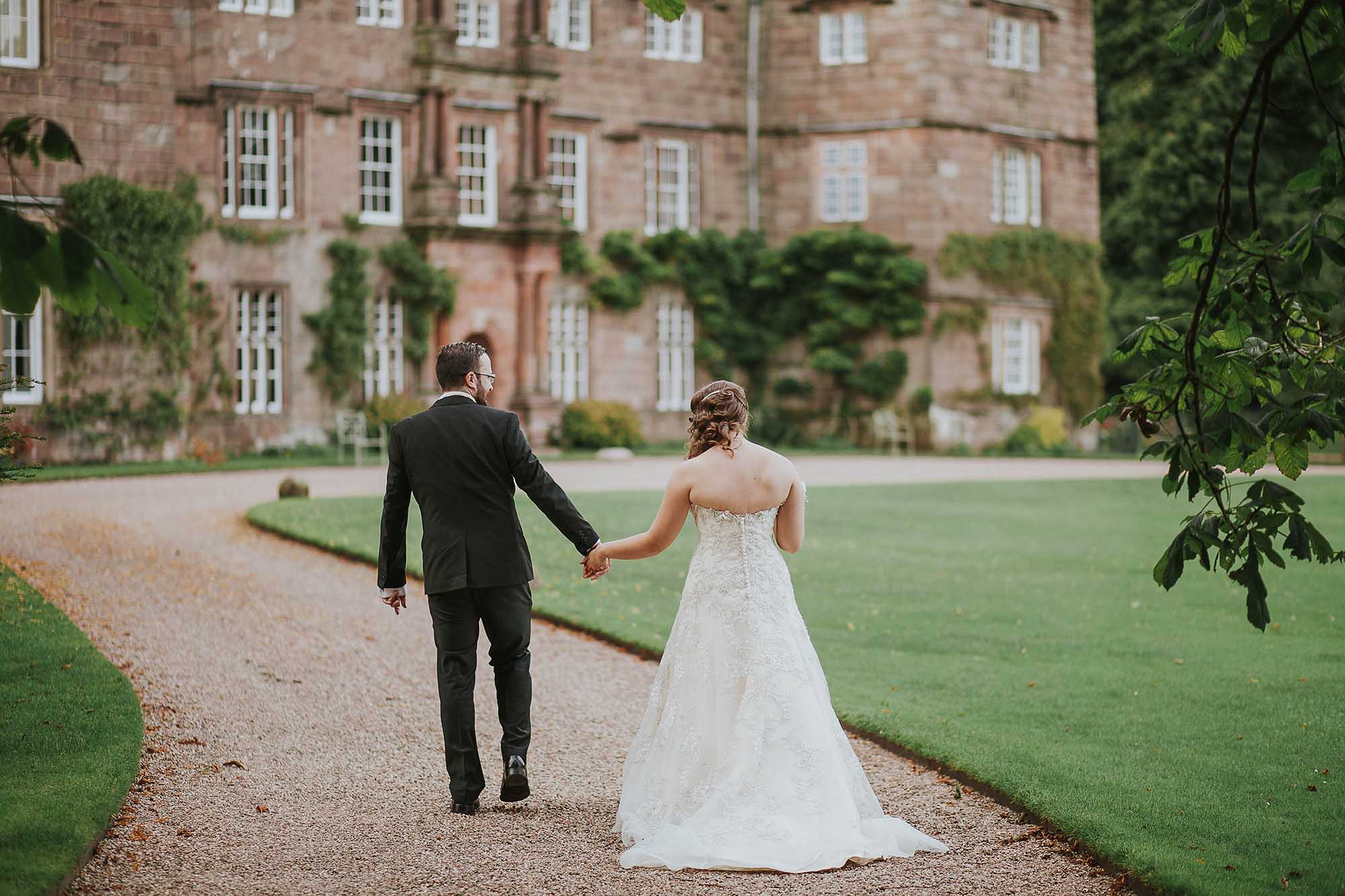 bride and groom walking outside Browsholme Hall and Tithe Barn