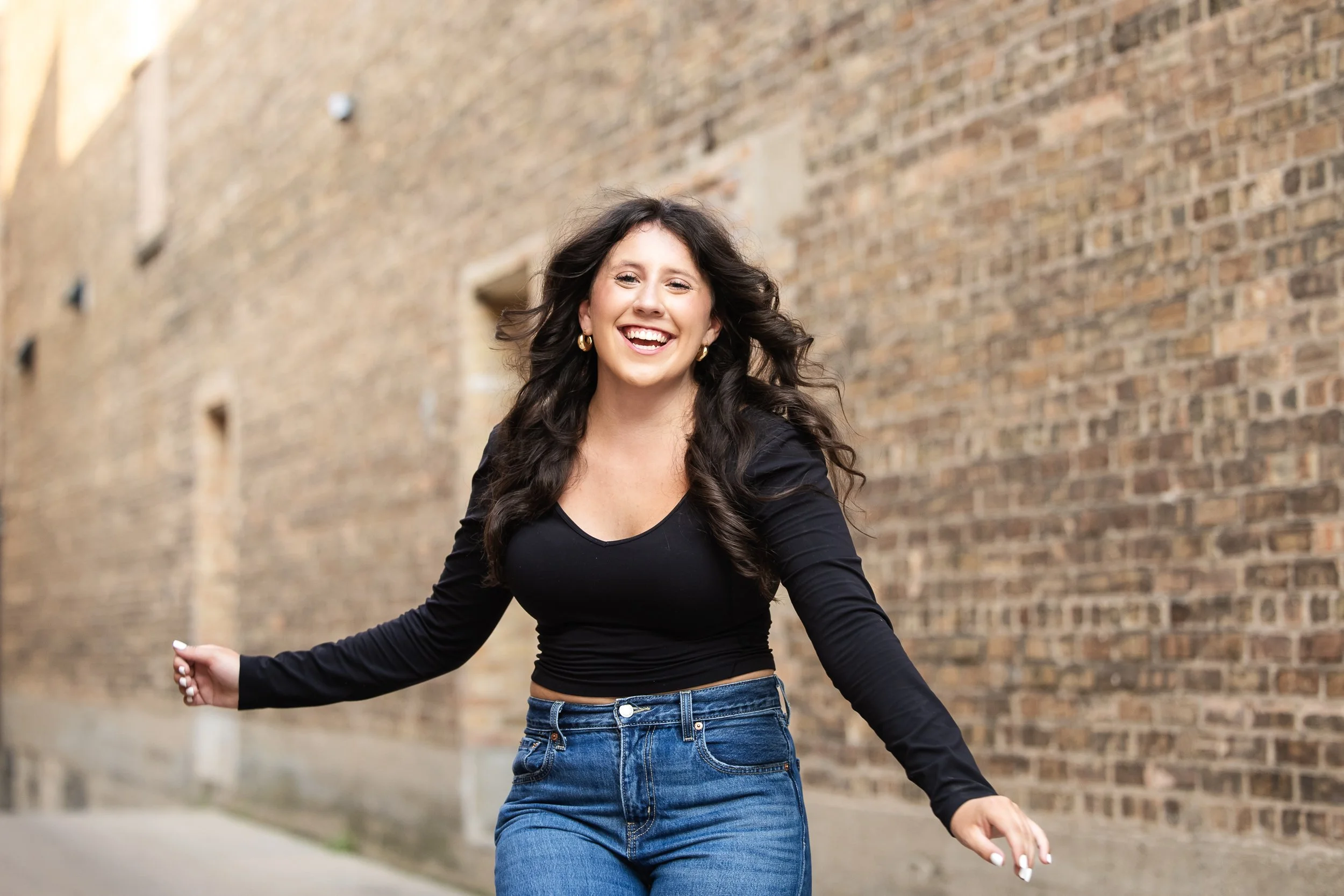 teen girl with open and energetic laugh walking in an alley with brick walls