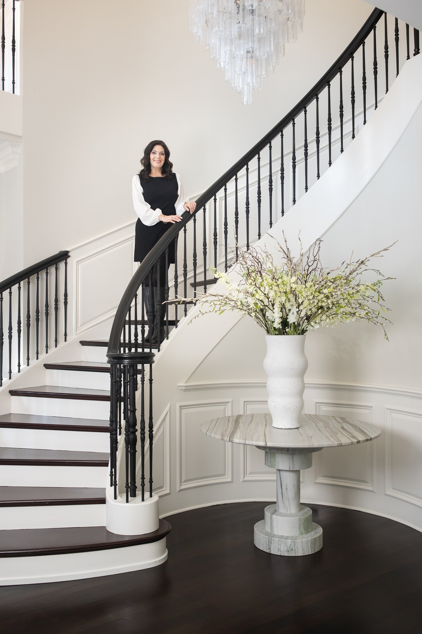 brand image of a woman interior designer standing on staircase in foyer. clean neutral aesthetic
