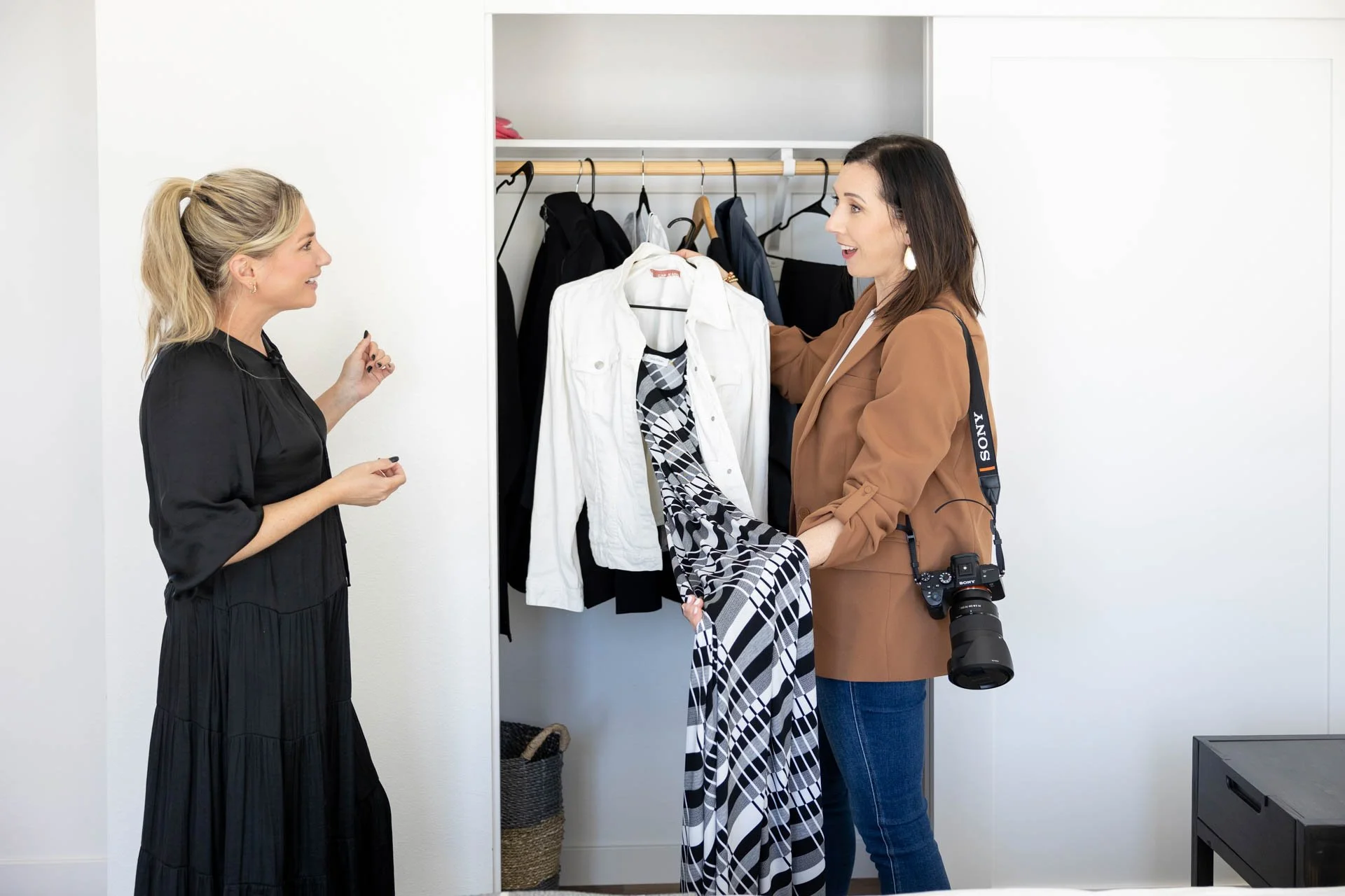 two women standing in front of a closet reviewing an outfit