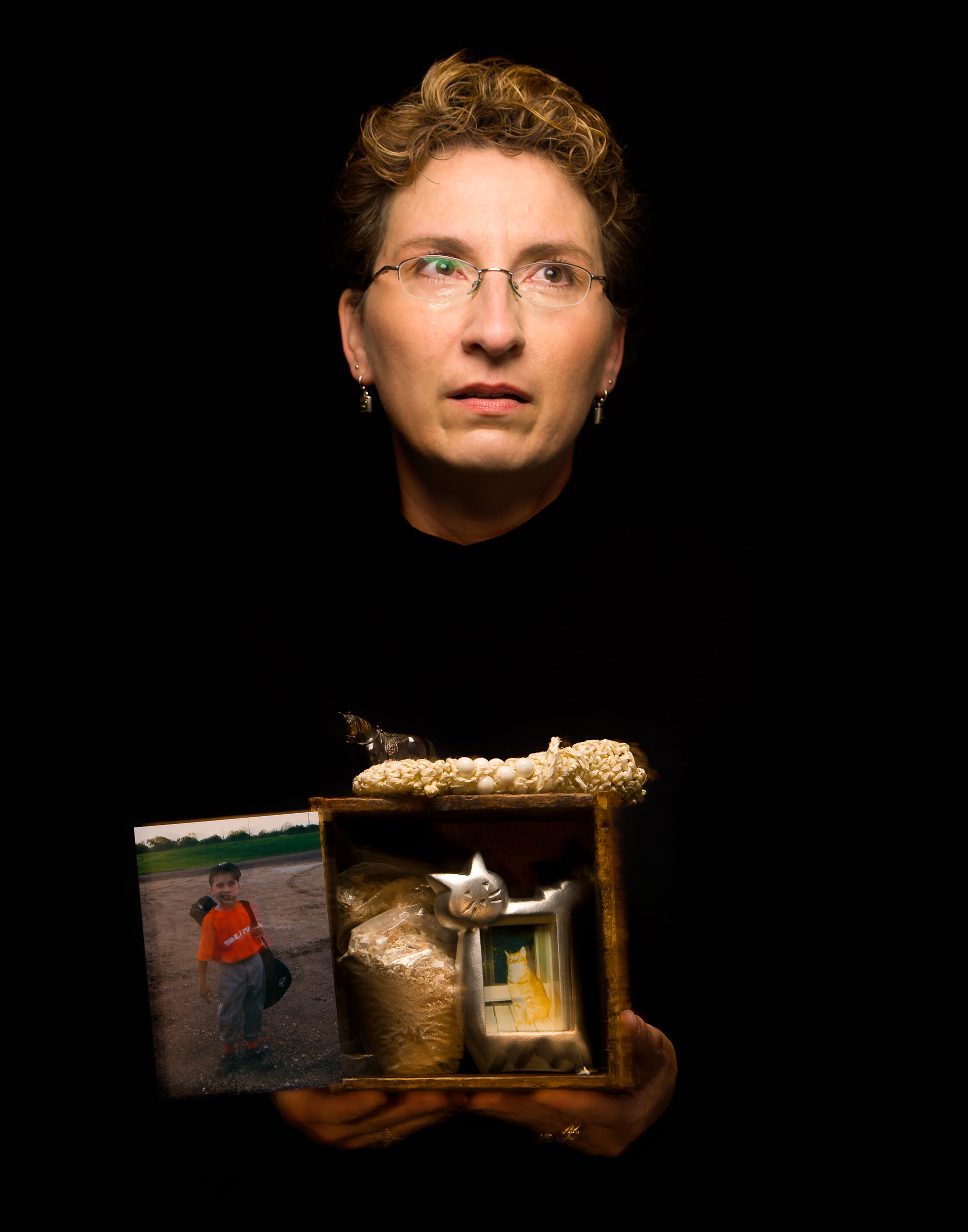 Life and Death The photo attached to the box is of my one and only son – he represents life. My box contains the cremated remains of my cat, Pumpkin, who came into my life when I needed her most – and I in one of her lives. She was there for me during some of the tougher parts of my life. The iron horse and straw/beaded bag represent my father who passed away when I was ten years old. Family and friends are the most important to me spiritually – hearts, minds and souls connect. Everyone and everything is born into this world for a reason. Lives cross at a time when one another is needed and when that time is over, we move on with our lives or proceed on to death. I, for one, am not afraid of death or dying. Until we meet again, Pumpkin, at the rainbow bridge……… Paula C. Lawrence, Kansas 2007