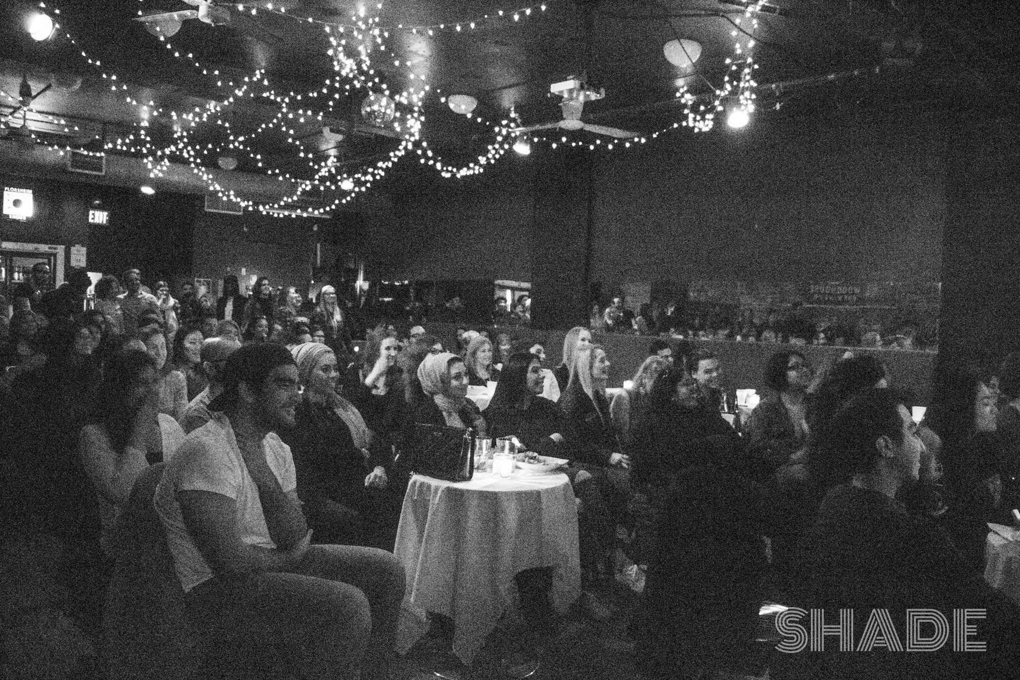 Audience watching one of Anasimone's productions in at the Rivoli featuring cute string lights.
