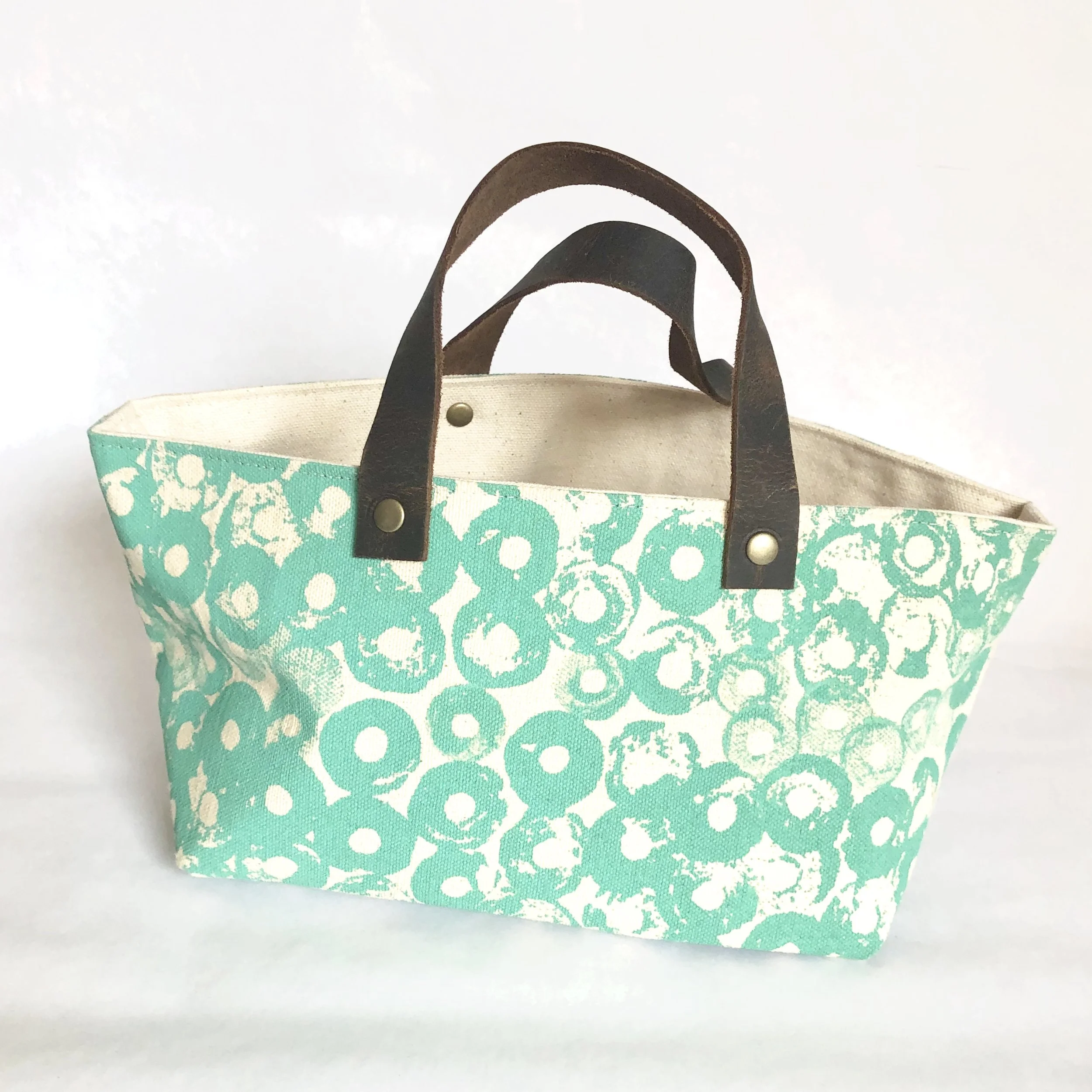 Cotton canvas storage bin featuring a circular thread spool design in green