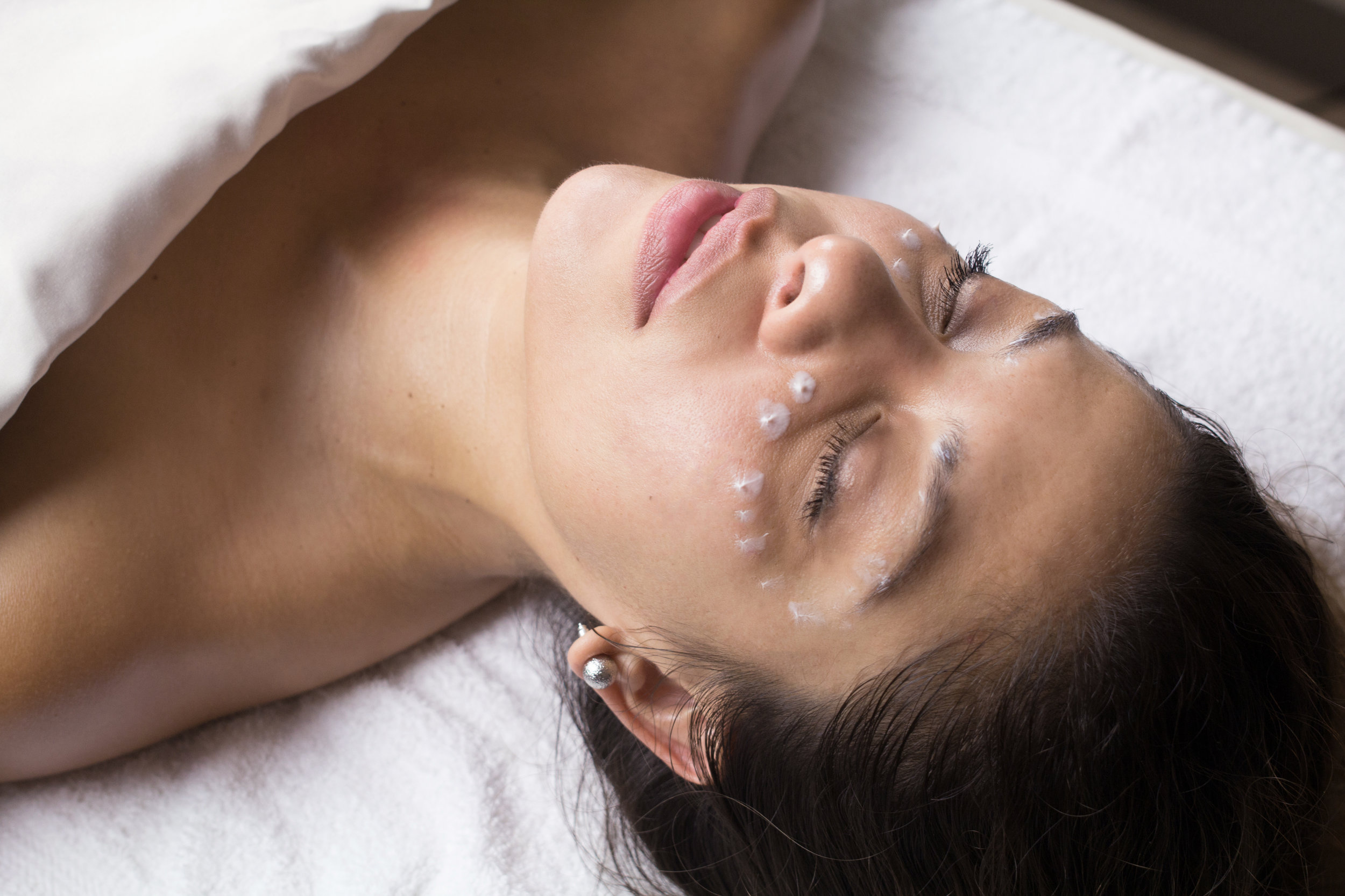 Eye cream dotted on a woman's face around her eye area during a facial