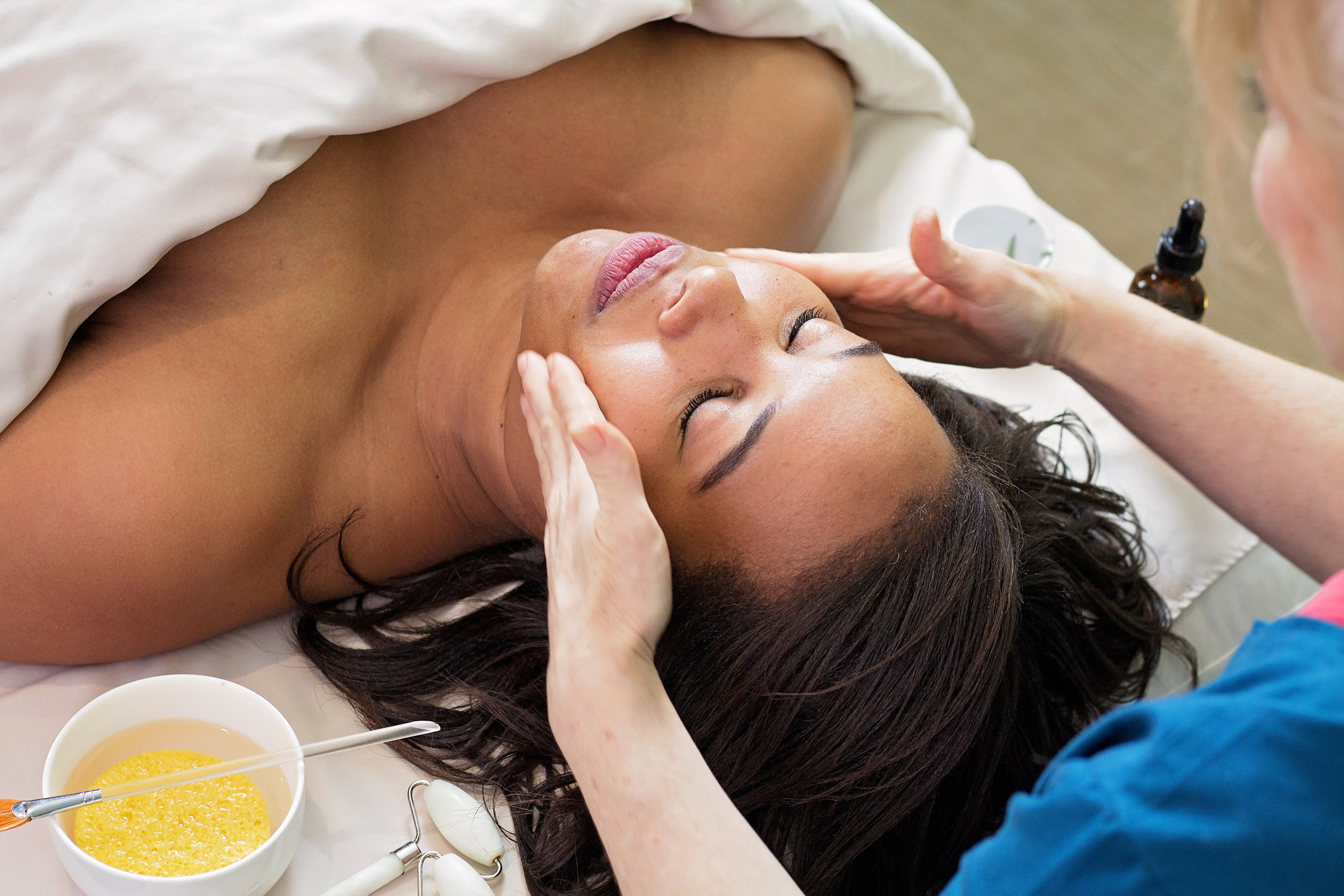 Cleanser being applied to a woman's cheeks during the second cleansing step during a Jalan Facial Spa facial