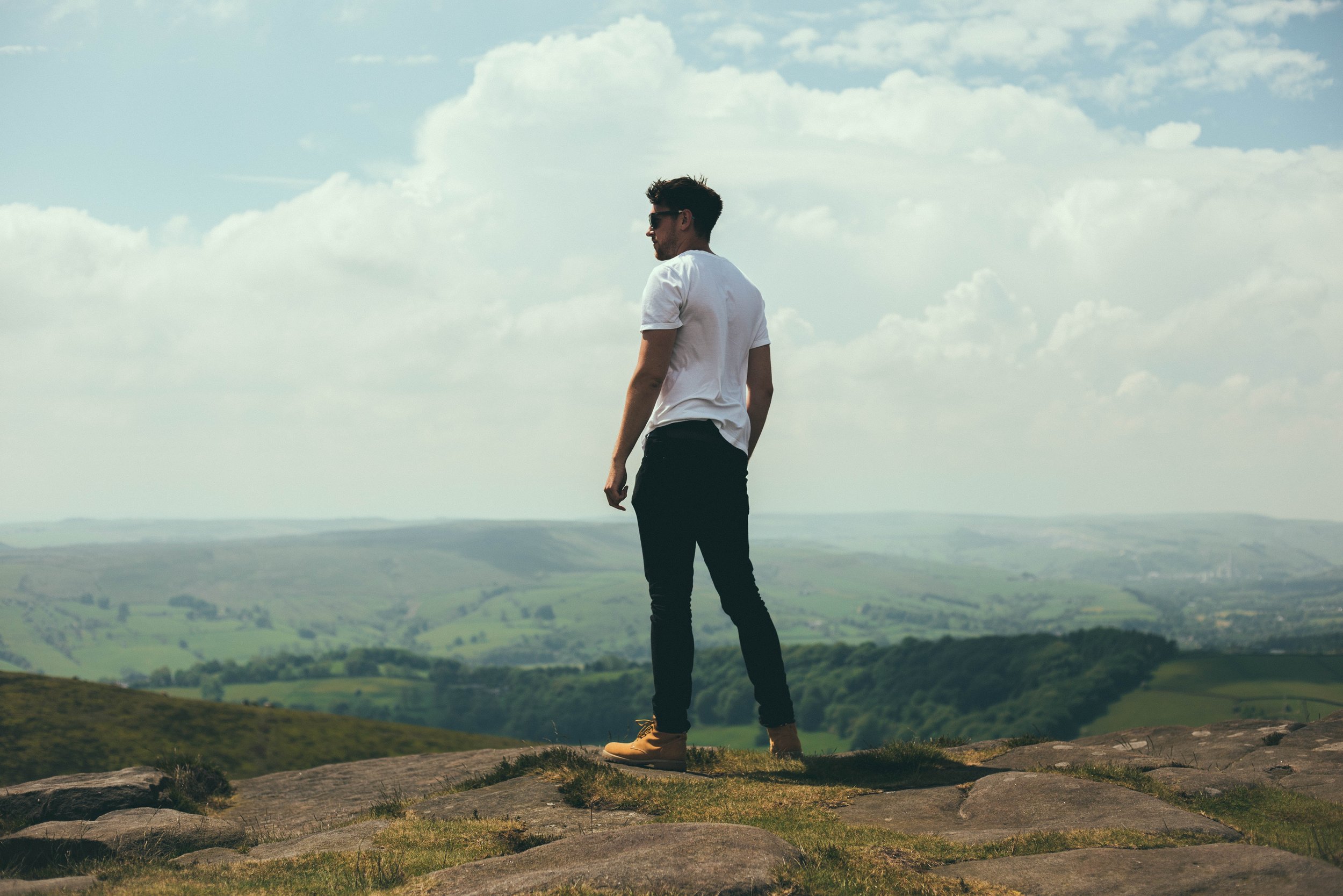 Man standing on a cliff overlooking the green mountains