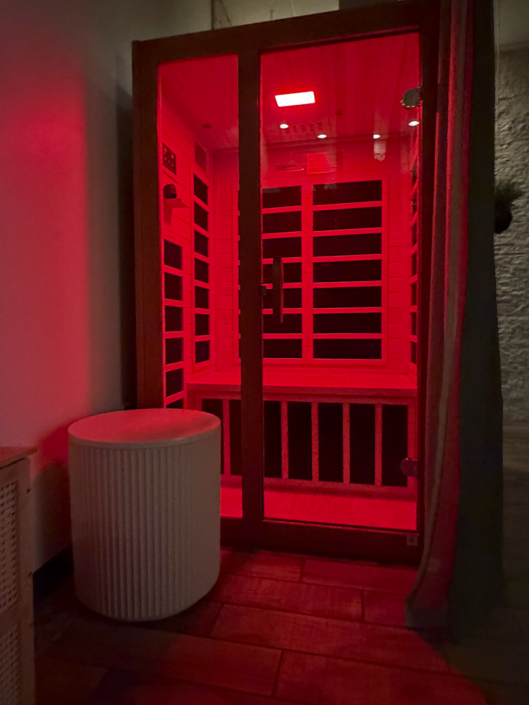 In the relaxing spa environment of Jalan Facial Spa, a square sauna with glass doors sits in the corner, as it glows in red light from the red light therapy.