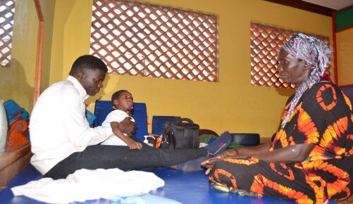 Children are frequently brought to Home of Hope for regular therapy.  Here, Joel, one of the therapists provides therapy for a patient while his caregiver looks on.