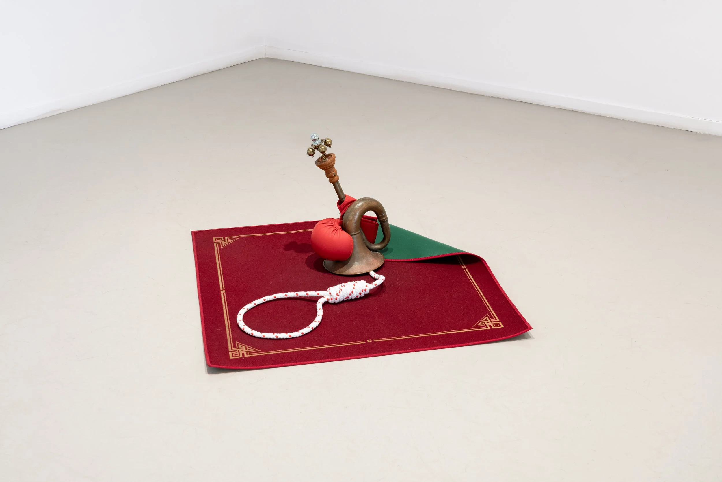 Le soliste se tait, 2023, tappeto da gioco, clacson, guantone da boxe, pendolo, corda, maniglia per mobile, sostegno di bastone per tenda, 40×113×74 cm