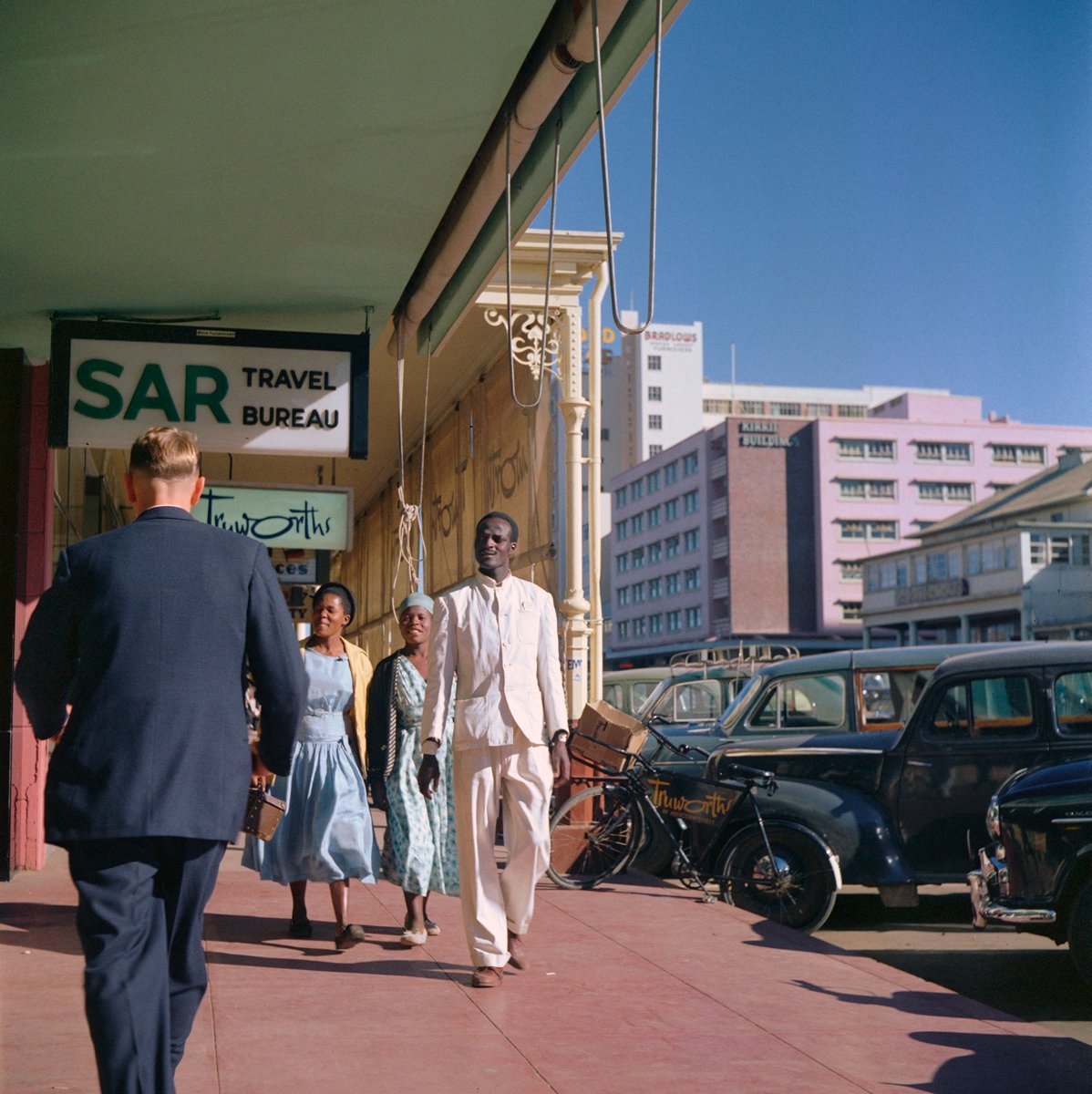  Todd Webb (United States, 1905-2000),  Untitled (44UN-7990-212), Southern Rhodesia (Zimbabwe)  [Pedestrians walking past SAR Travel Bureau, Truworths, and other shops, Bulawayo] ,  1958, archival pigment print, 14 x 14 inches (image), 16 x 16 inches