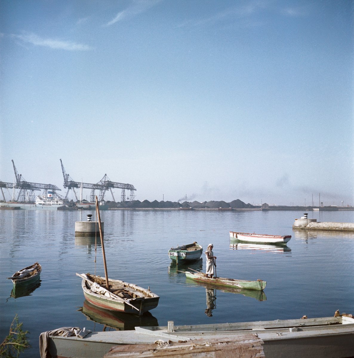  Todd Webb (United States, 1905-2000),  Untitled (44UN-7961-222), Sudan  [Man poling a boat through the harbor, with oil rigs in the background] ,  1958, archival pigment print, 20 x 20 inches (image), 22 x 22 inches (sheet). © Todd Webb Archive 