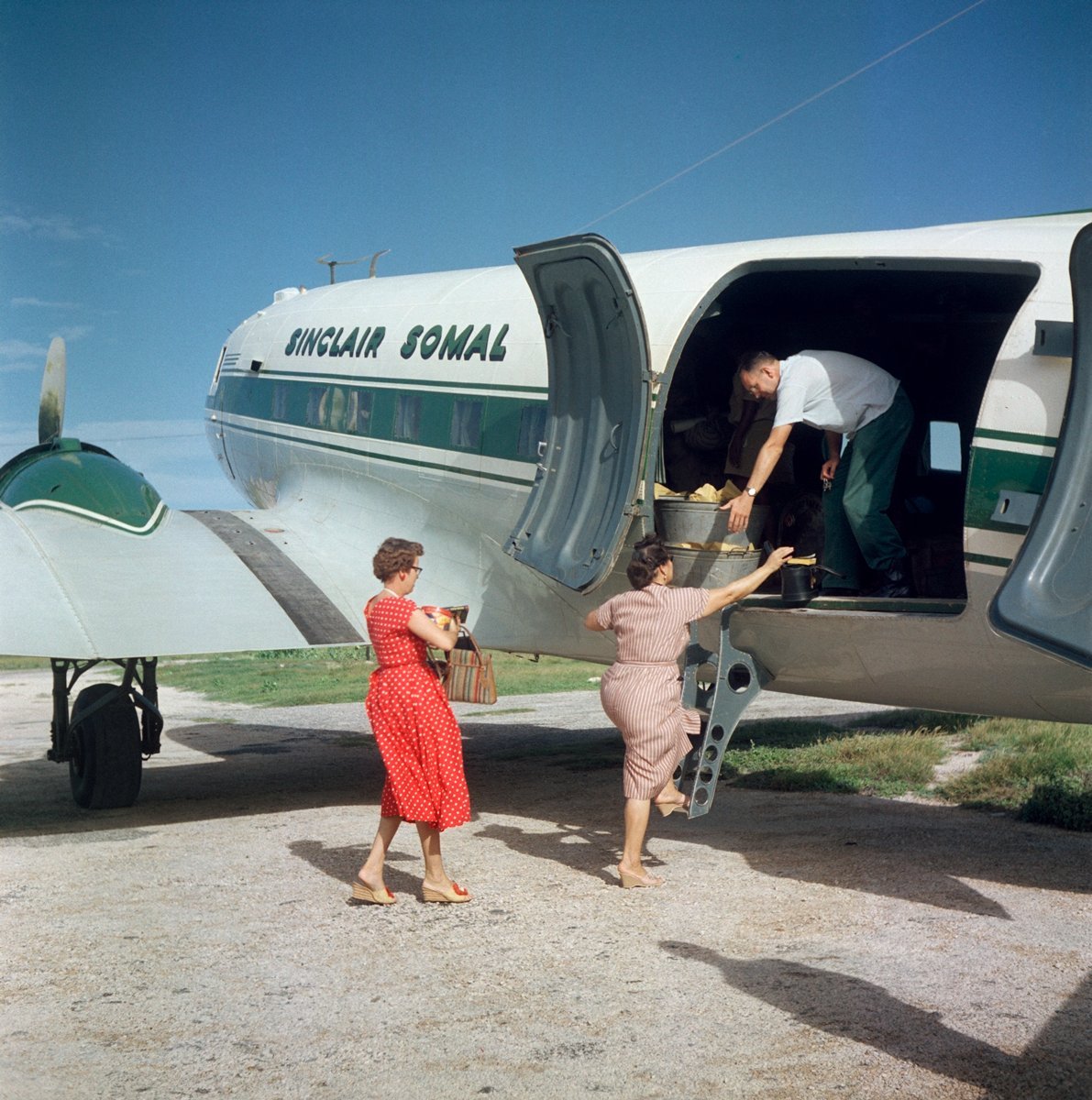  Todd Webb (United States, 1905-2000),  Untitled (44UN-7968-001), Somaliland (Somalia)  [Women stepping up into a Sinclair Somal airplane], 1958, archival pigment print, 12 x 12 inches (image), 14 x 14 inches (sheet). © Todd Webb Archive 