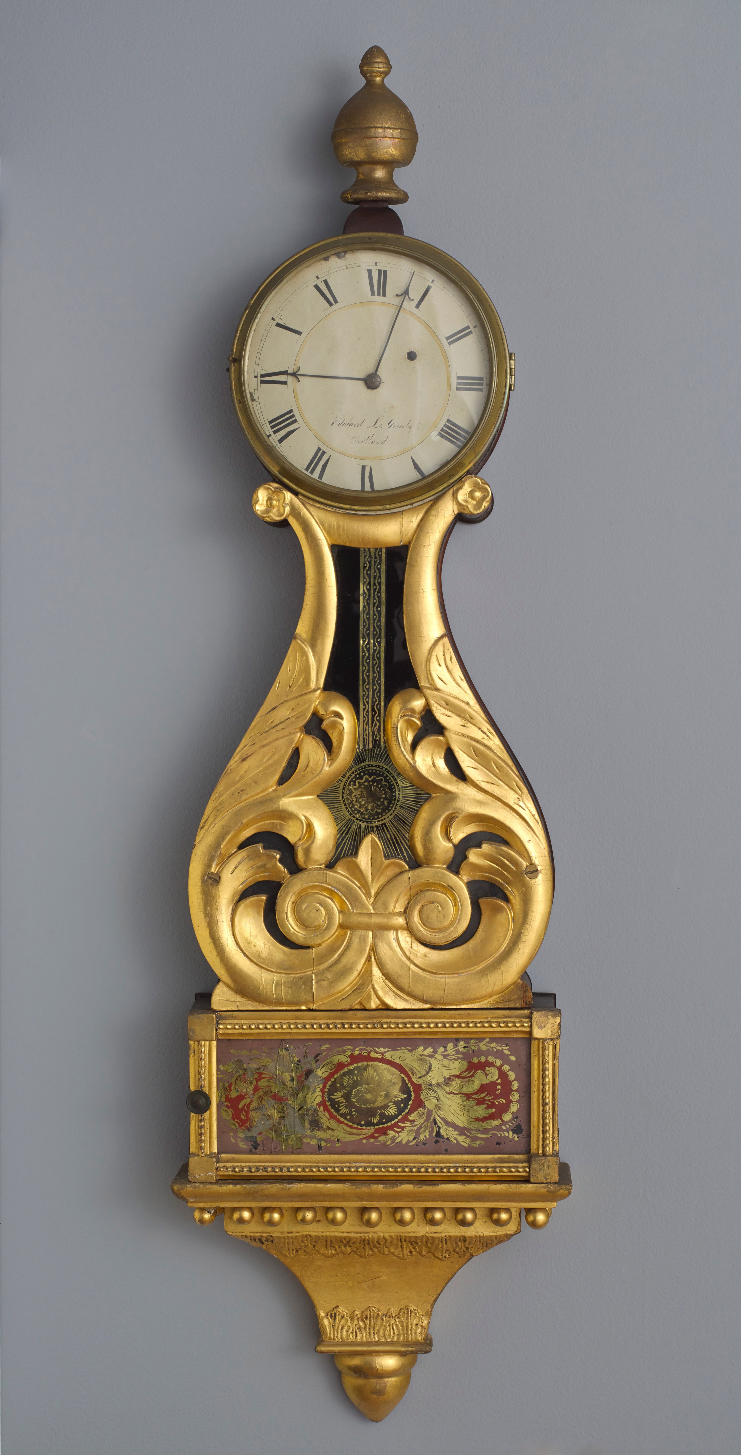   Edward Grueby  United States, 1808–1896  Wall Clock , 1830–1839 pine, brass, gilt, and verre églomisé, 41 1/2 x 11 3/4 x 3 7/8 inches Museum purchase with support from Friends of the Collection, the Margaret H. Jewell Fund, Mr. and Mrs. Fletcher Br