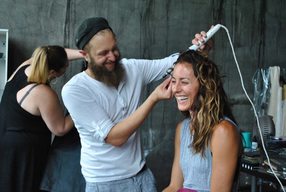  Hair Stylist  Michael Sparto  starts working on dancer  Meredith Hogan 's hair while Makeup Artist  Hannah Dorton  works on a model in the background. 