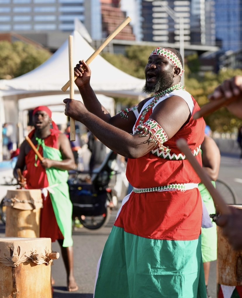 Burundian drummers dress in red, green, and white cheer on runners at the finish line at Run For The Water