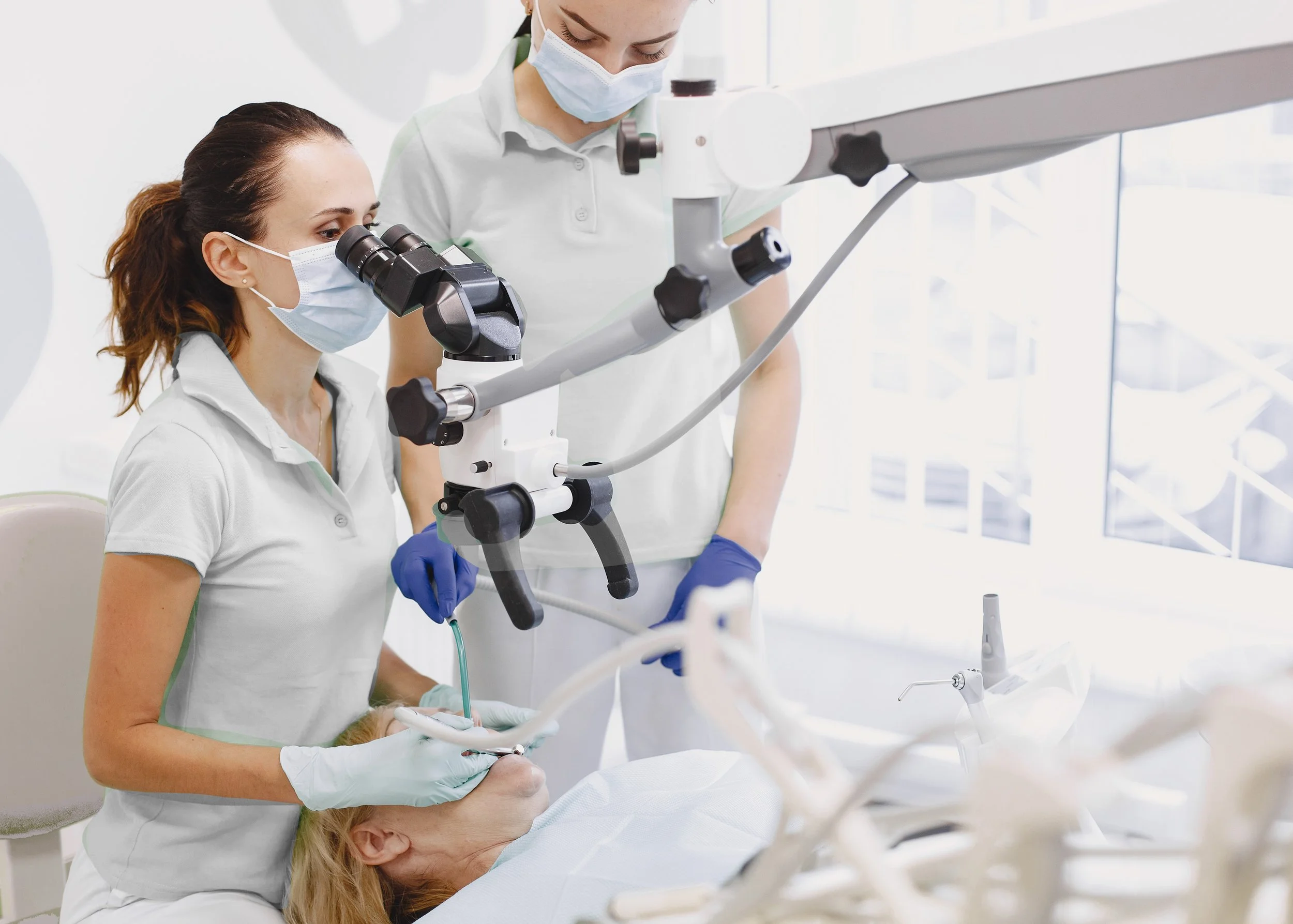 Doctora con mascarilla y guantes usando un microscopio en el quirófano del centro odontologico prof.dr. Alexis Chudnovsky
