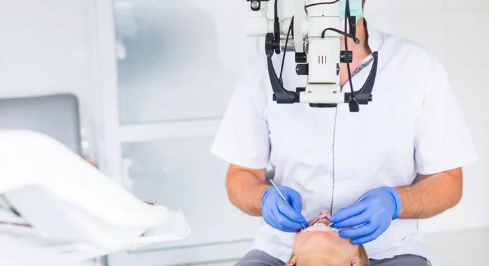 Médico usando un microscopio para hacer una examinación ocular a un paciente en un consultorio.