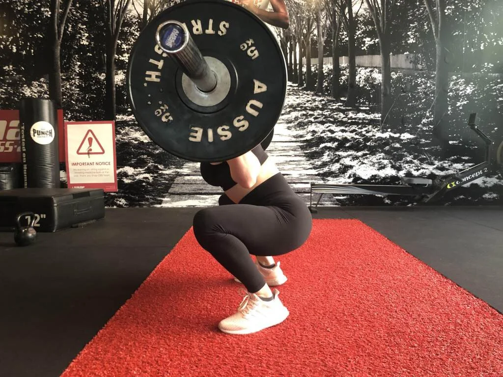 Squat with your hips below parallel while keeping your feet flat on the ground and your knees tracking straight