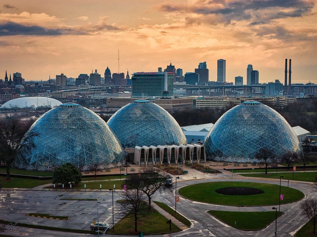 The three Mitchell Park Domes beneath the Milwaukee skyline at sunset.