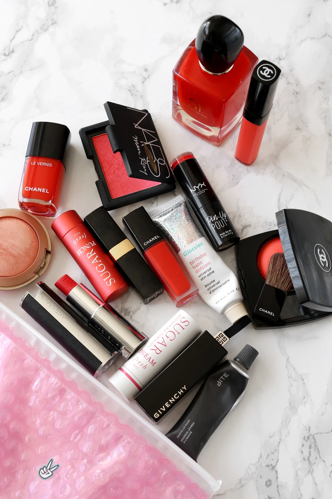 What's in my pink Glossier makeup bag - lots and lots of orange-red lipsticks and Armani's new SÌ Passione scent . 