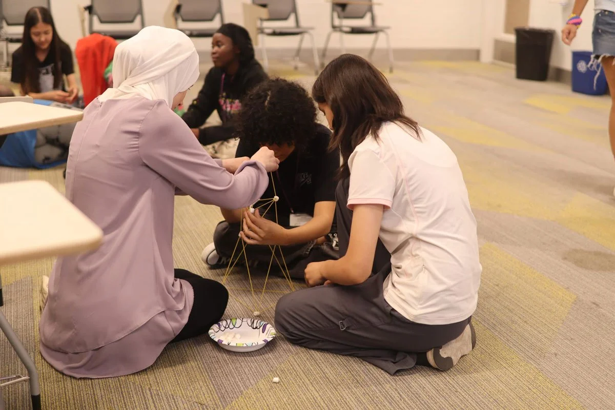 Students building a project using sticks and marshmallows 