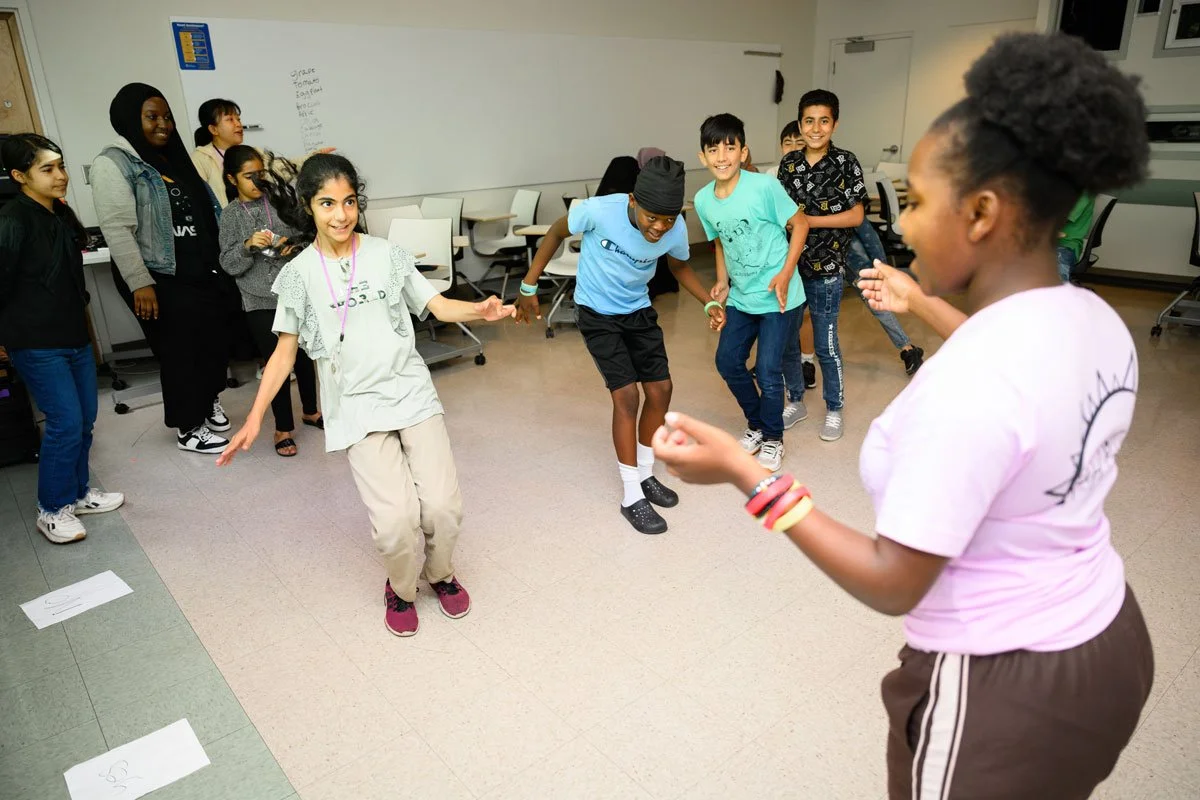 Kids in a classroom learning a dance together