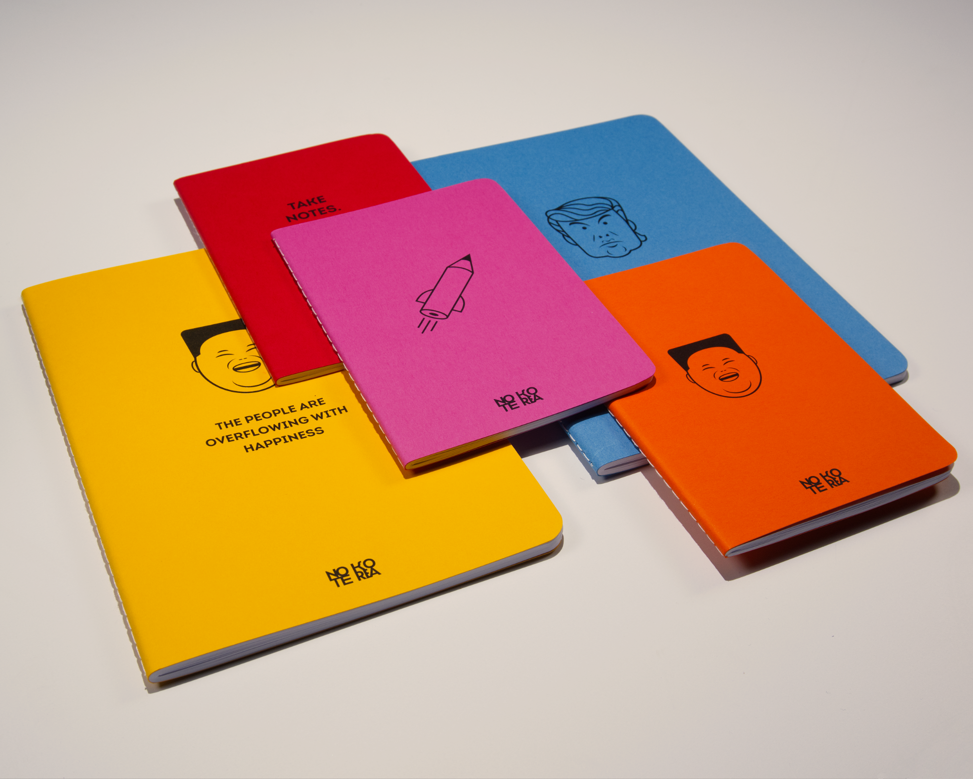 Colorful notebooks with illustrations and text, arranged on a white surface.