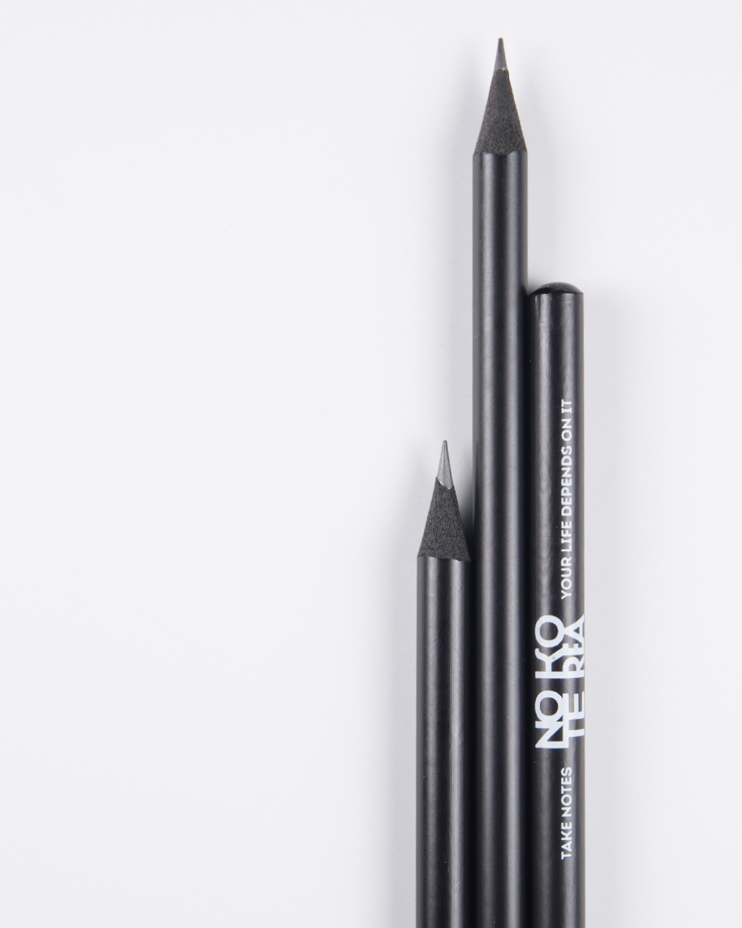 Three black Note Korea™ pencils on a white background, two with sharpened tips and one with a rounded tip, featuring white text on the side.