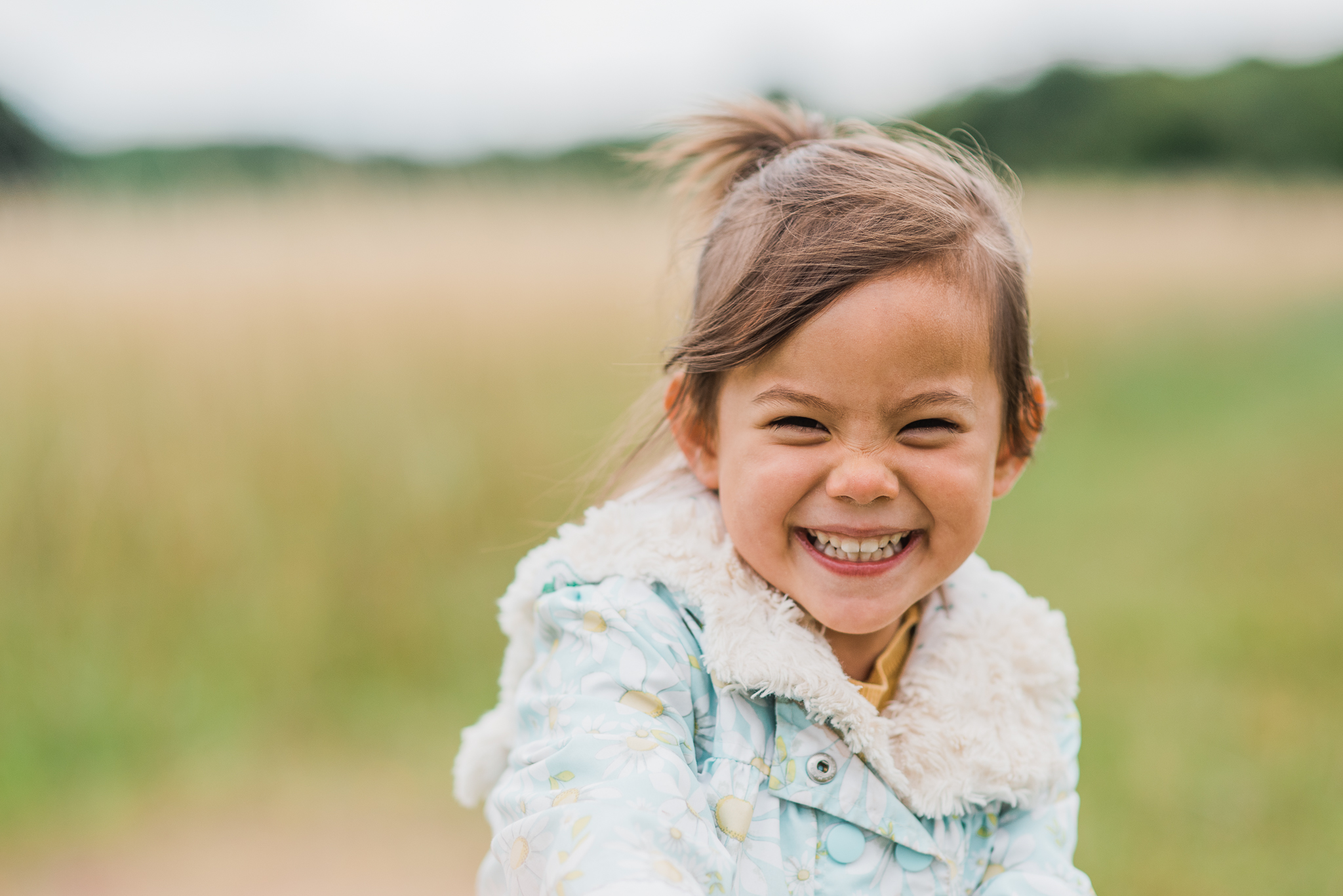 Girl smiling and running in field Cotswolds Child  Photographer.jpg