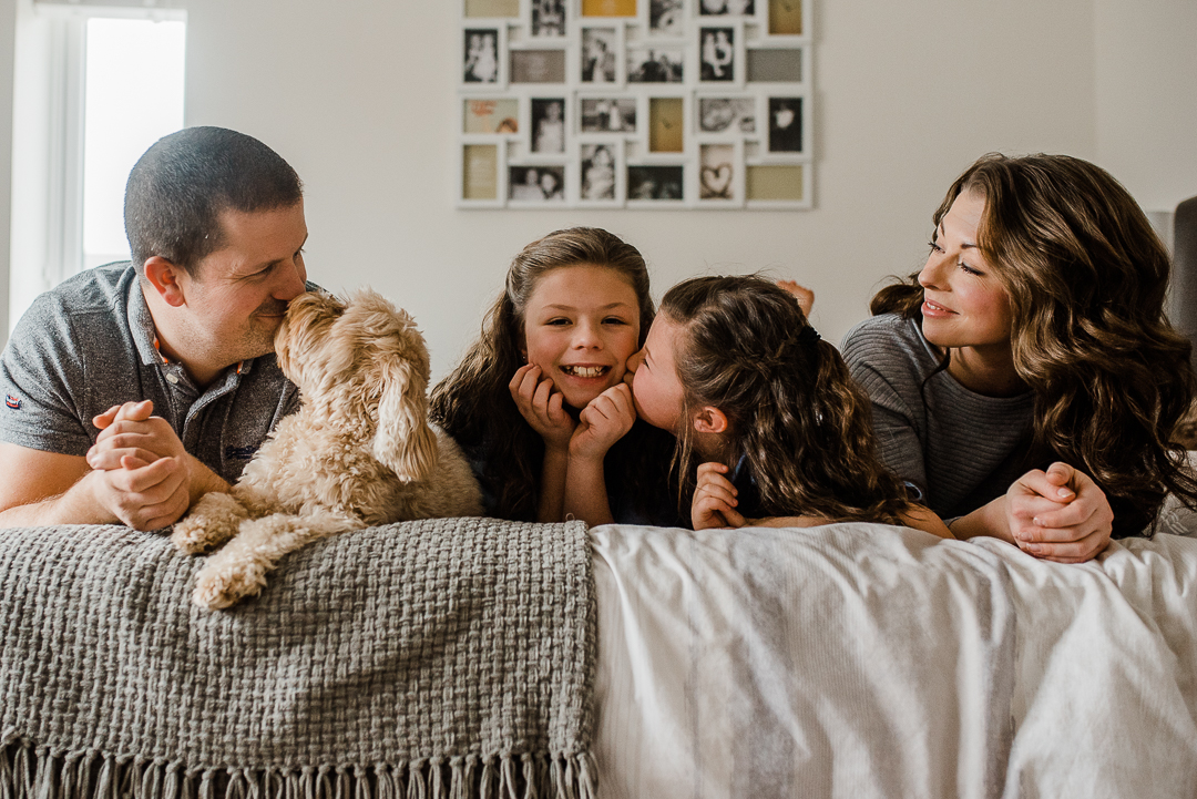 Happy family of four in bedroom with dog