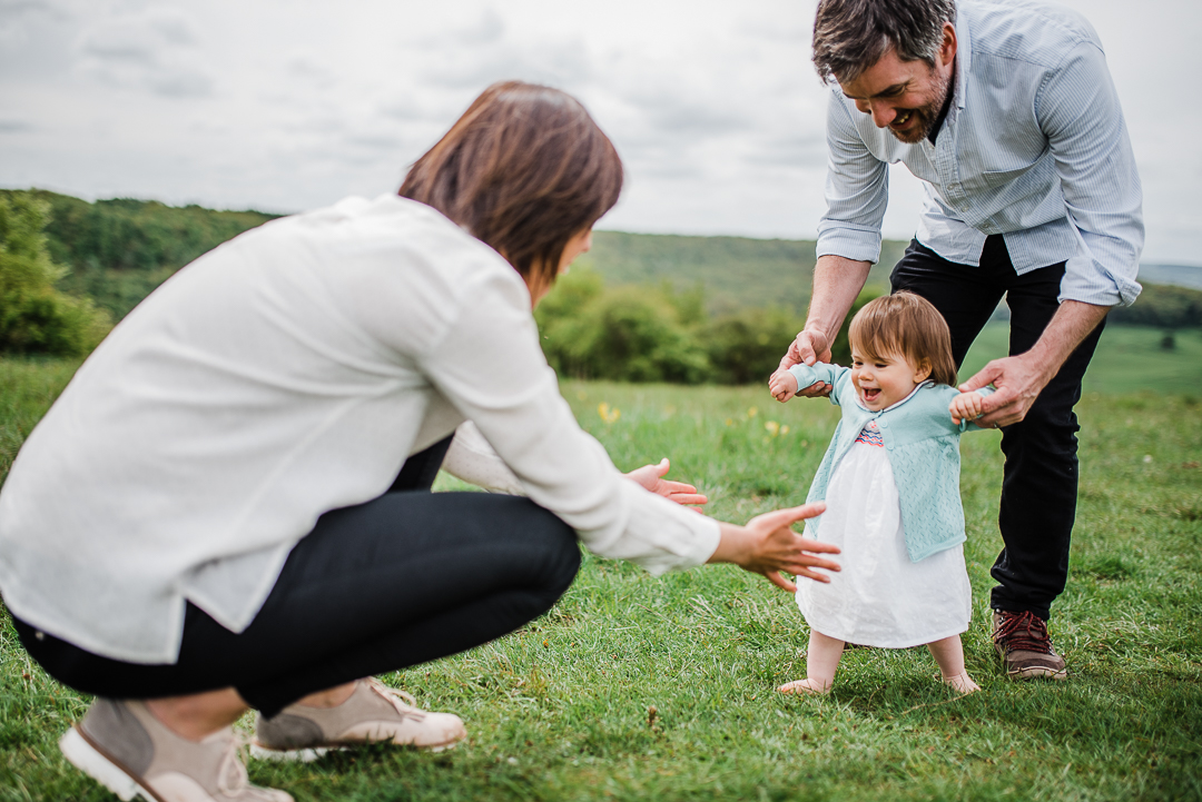 1 year old girl walking smiling parents holding hands