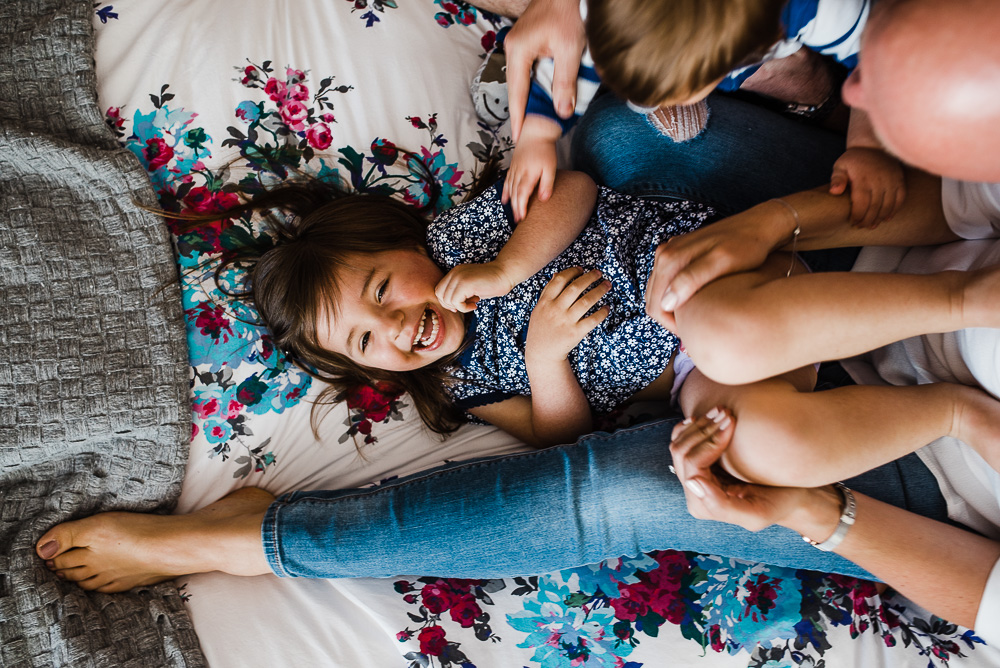 tickles and giggles on bed in home photography