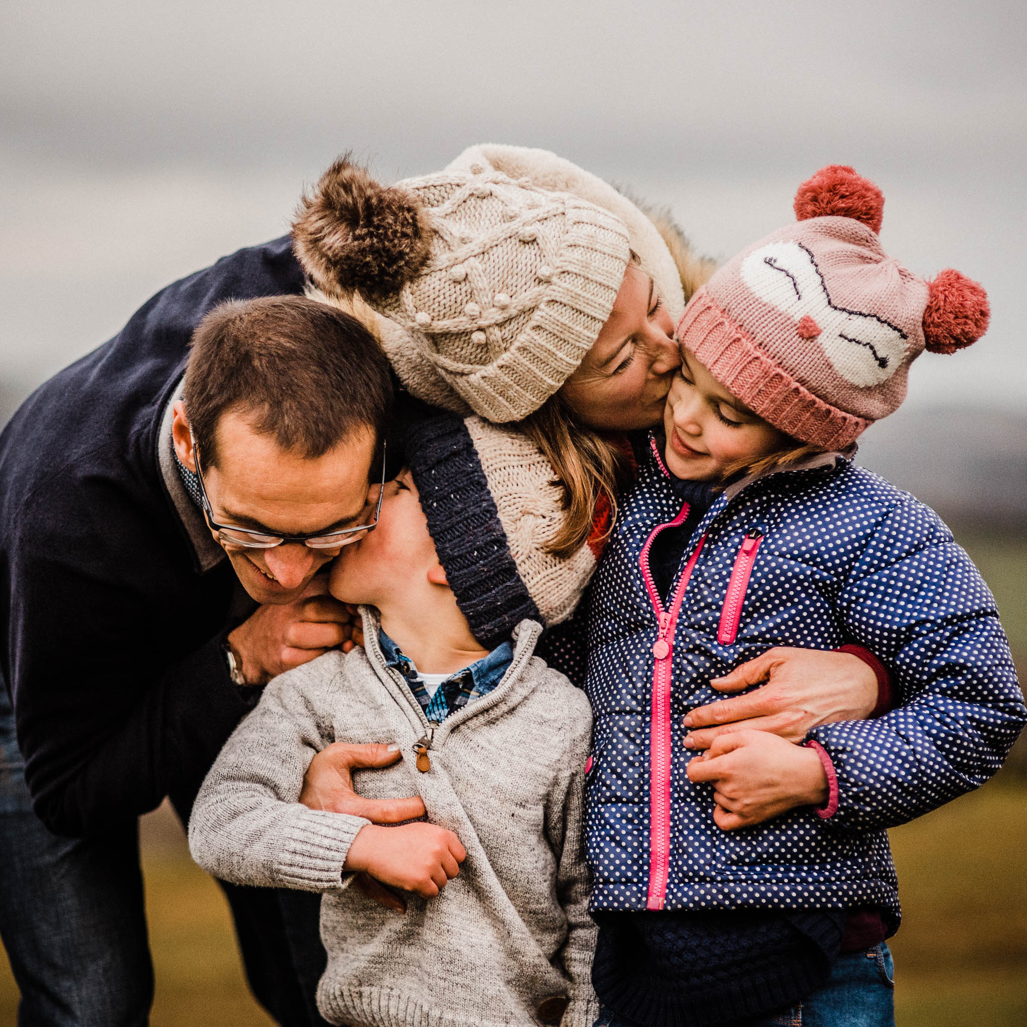 family of four with bobble hats on hill in cheltenham photoshoot