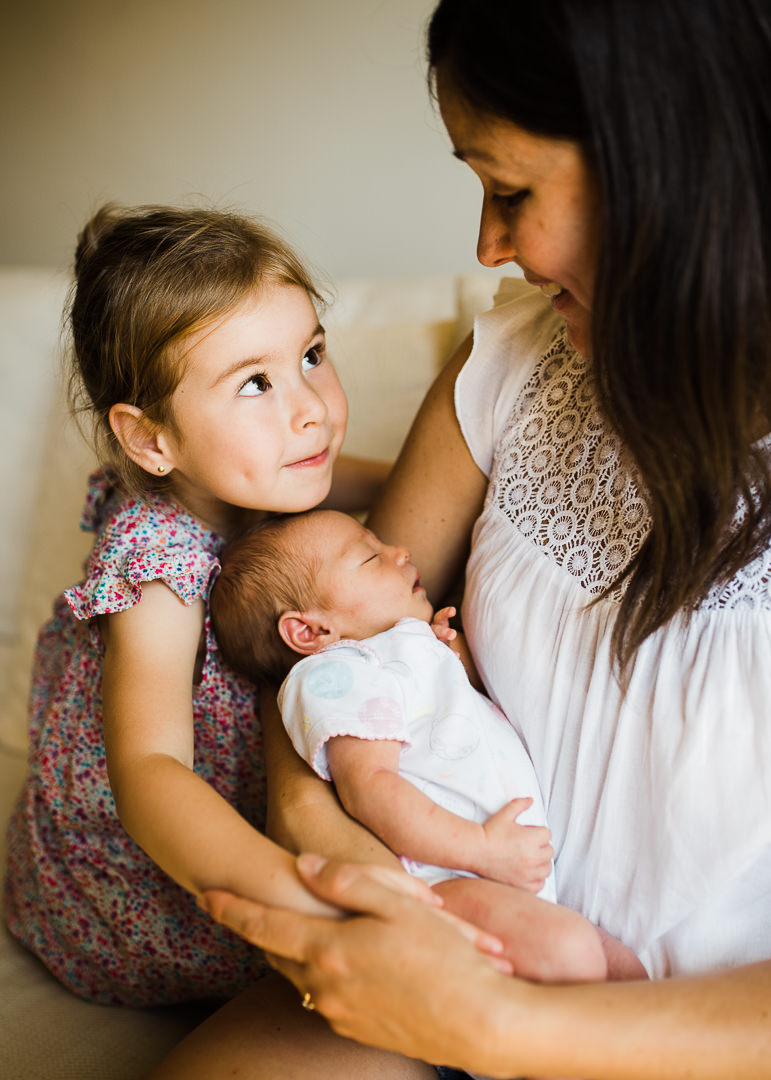 Newborn baby with big sister and mummy