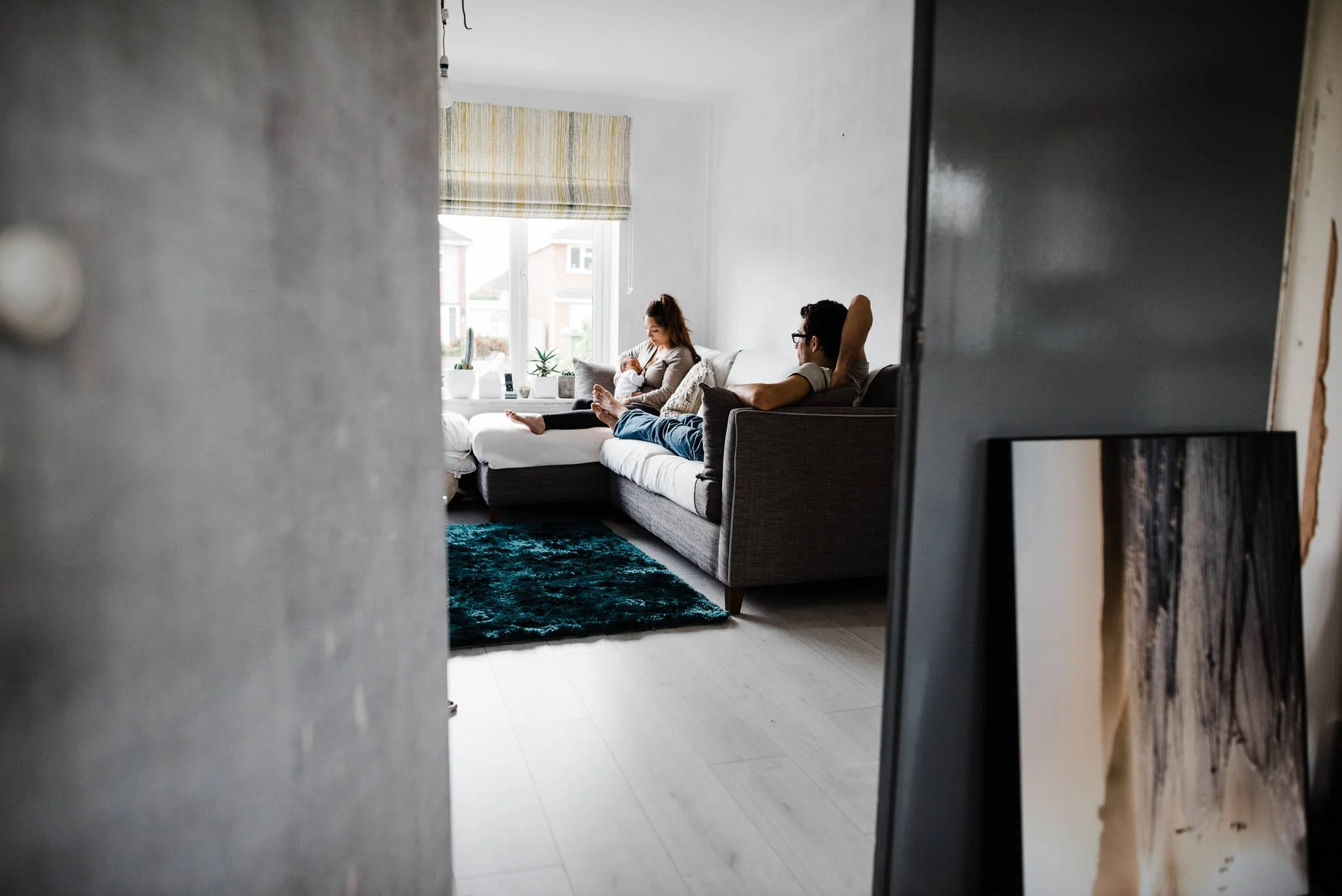 Photo of Newborn baby and parents on sofa at home. baby is asleep and relaxed