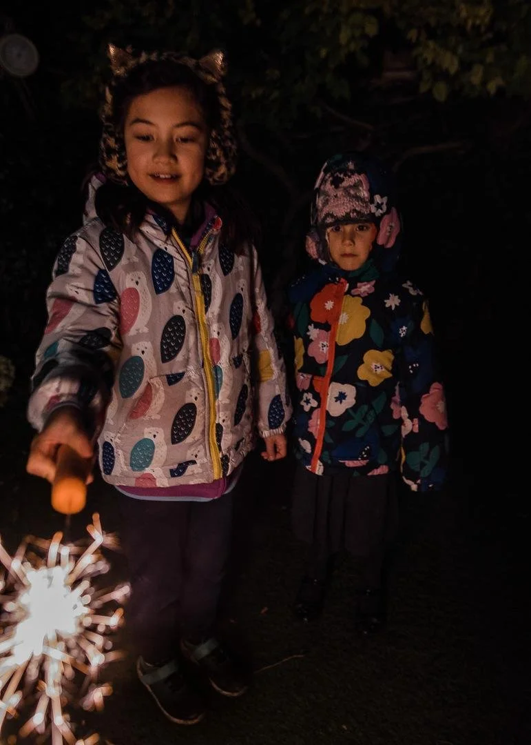 Two young girls playing with a sparkler on firework night