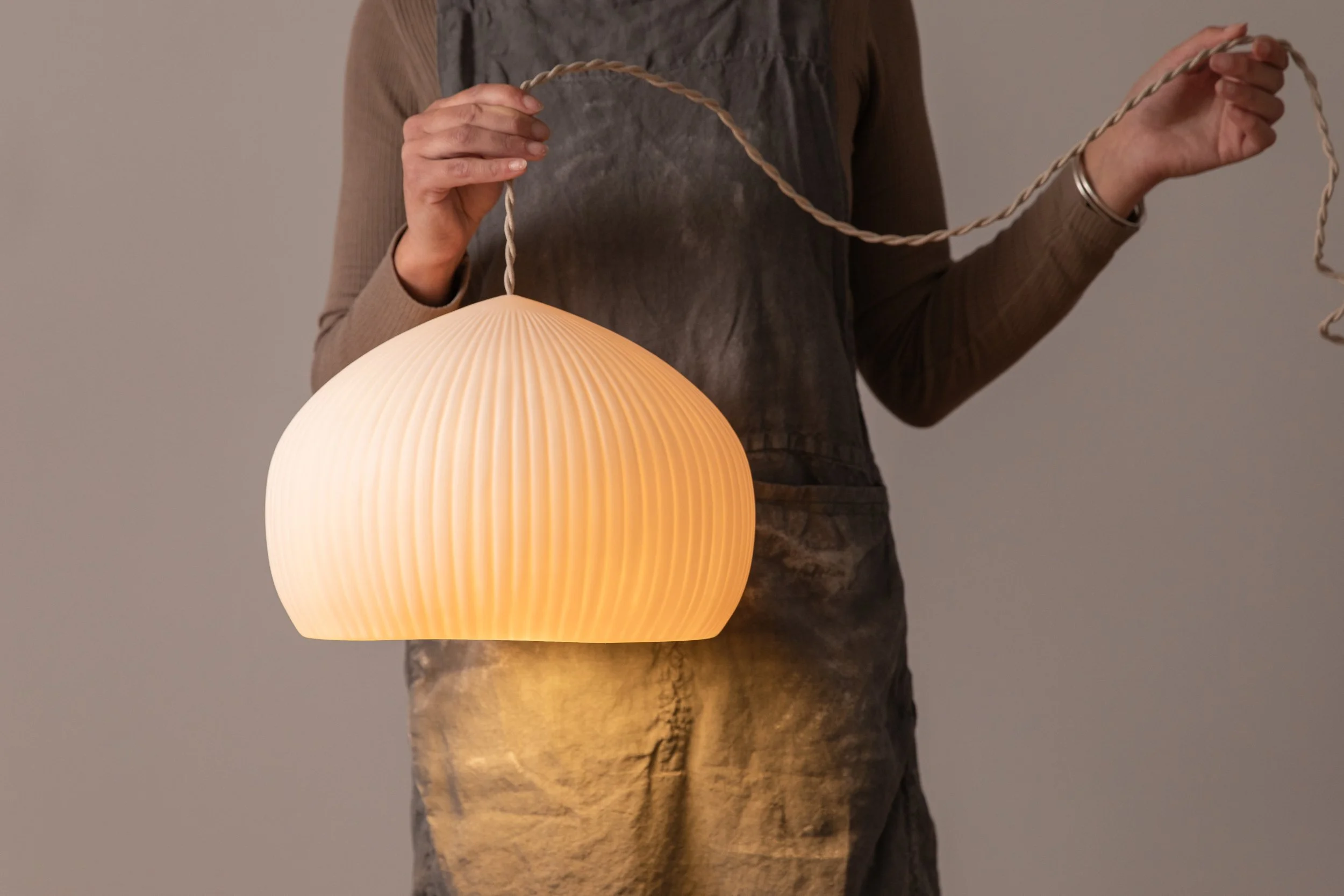 Pippi & Meceramics eatra large porcelain Morfar pendant with ribbed detail, held in hand to show size and lit.jpg